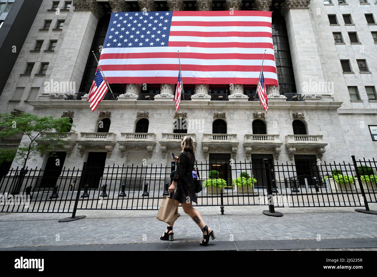 director Profesor de escuela Relajante Una mujer pasa por delante de la fachada de la Bolsa de Valores de Nueva  York cubierta con una gran bandera estadounidense, Nueva York, NY, 6 de  julio de 2022. Las acciones