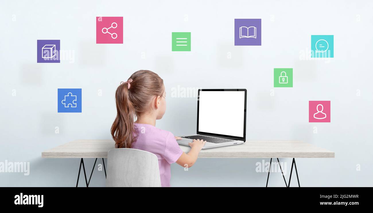 Una niña pequeña trabaja en un ordenador portátil. Concepto de Internet de las cosas. Pantalla de portátil aislada para mockup. Los iconos flotan sobre la tabla Foto de stock