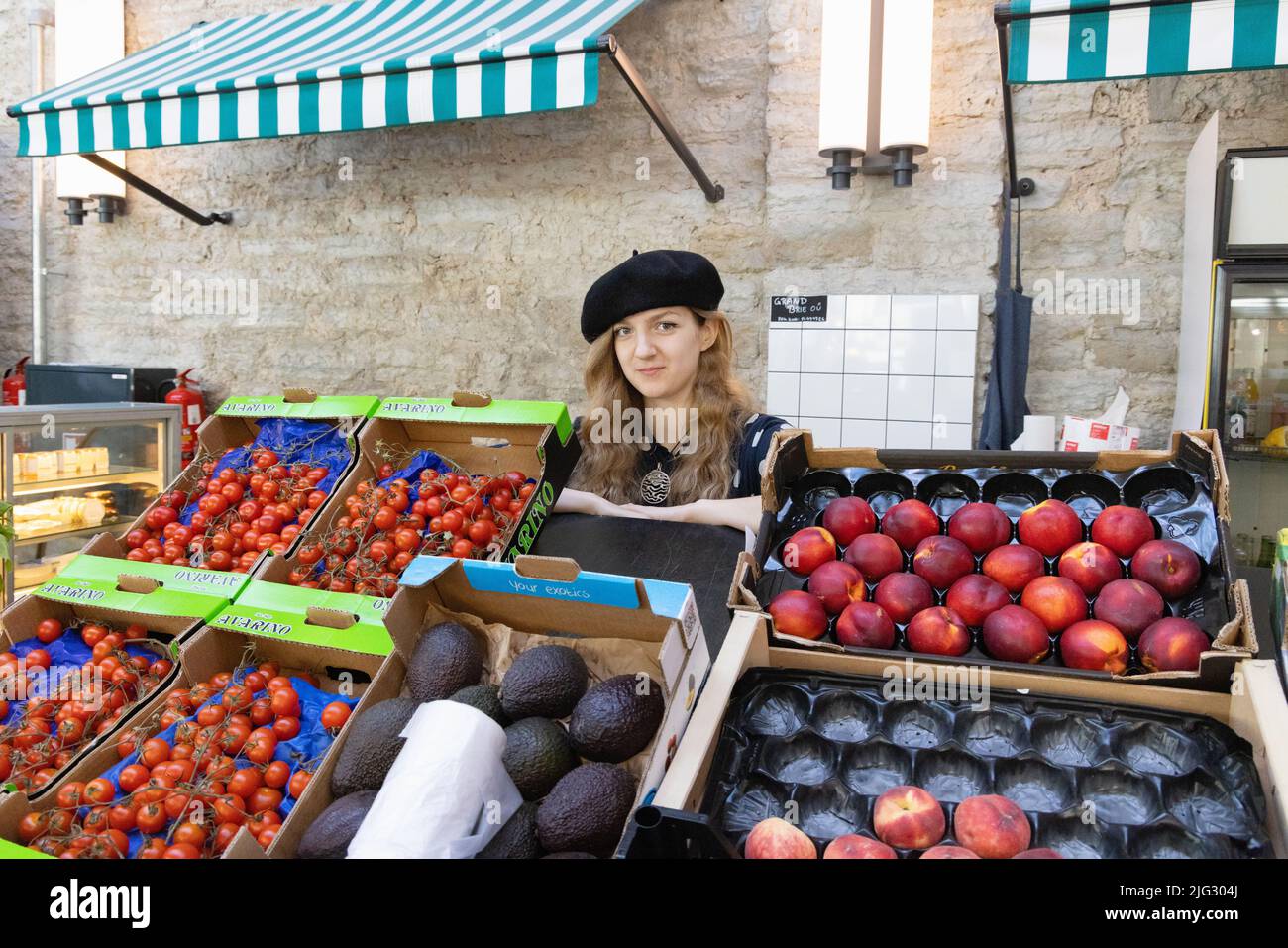 Tallinn Lifestyle; una mujer de 20s años que vende fruta en su puesto de comida, el mercado Balti Jaam, un gran mercado interior, Tallinn Estonia Europa Foto de stock