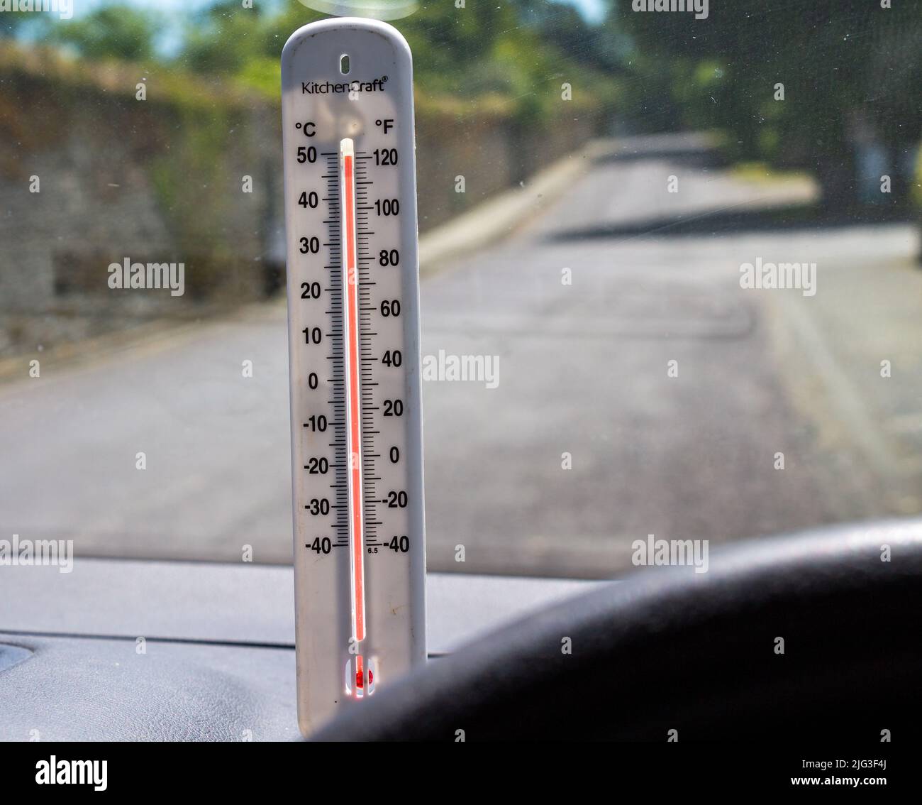 Termómetro de temperatura que muestra temperaturas peligrosas para mascotas en el coche con las ventanas cerradas estacionadas a la luz del sol Foto de stock