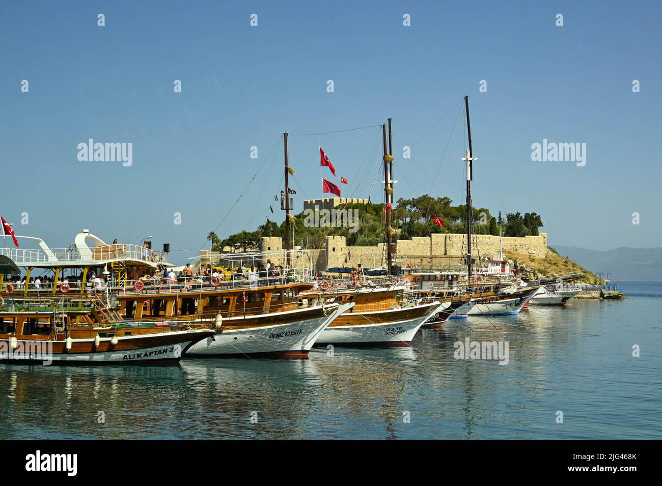 Kusadasi, Turquía - Junio 2022 de mayo: Fila de barcos turísticos amarrados en el puerto con la Isla Pigeon en el fondo Foto de stock