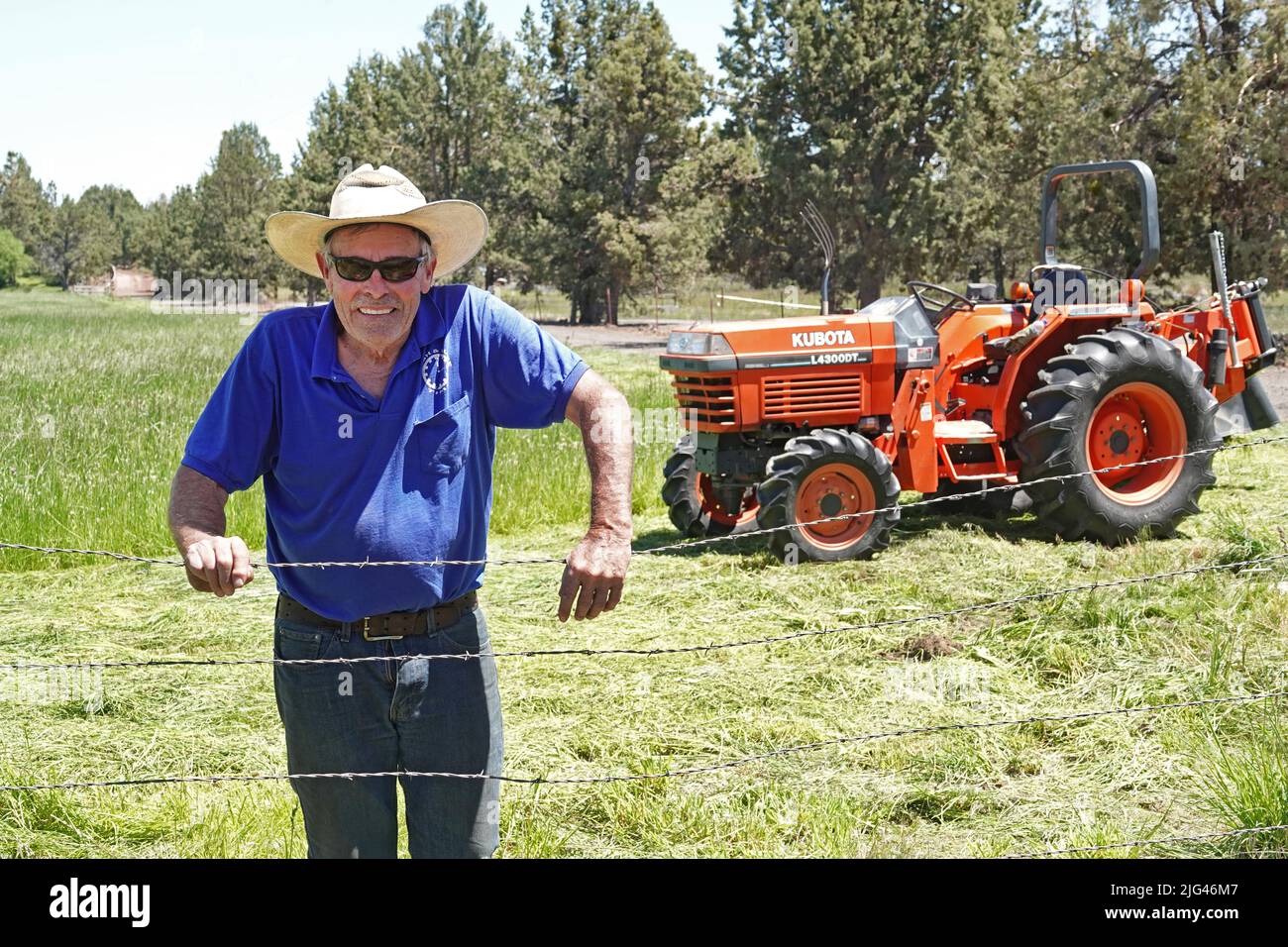 Granjero en un campo de heno de pasto con su tractor, Bend, Oregon Foto de stock