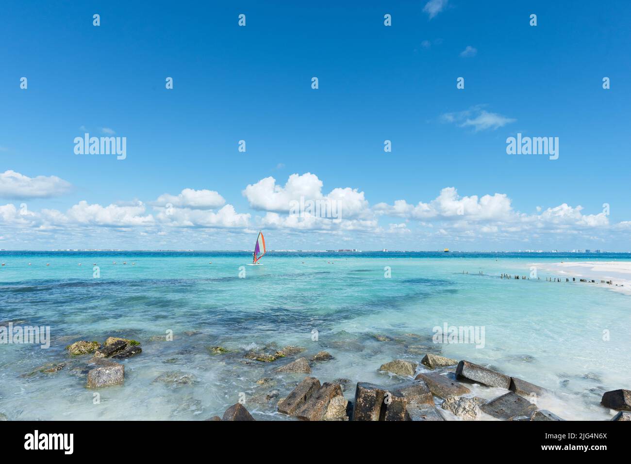 Hombre irreconocible haciendo windsurf cerca de una playa tropical en Isla Mujeres, México. En el fondo está el cielo azul. Concepto de vacaciones deportivas Foto de stock