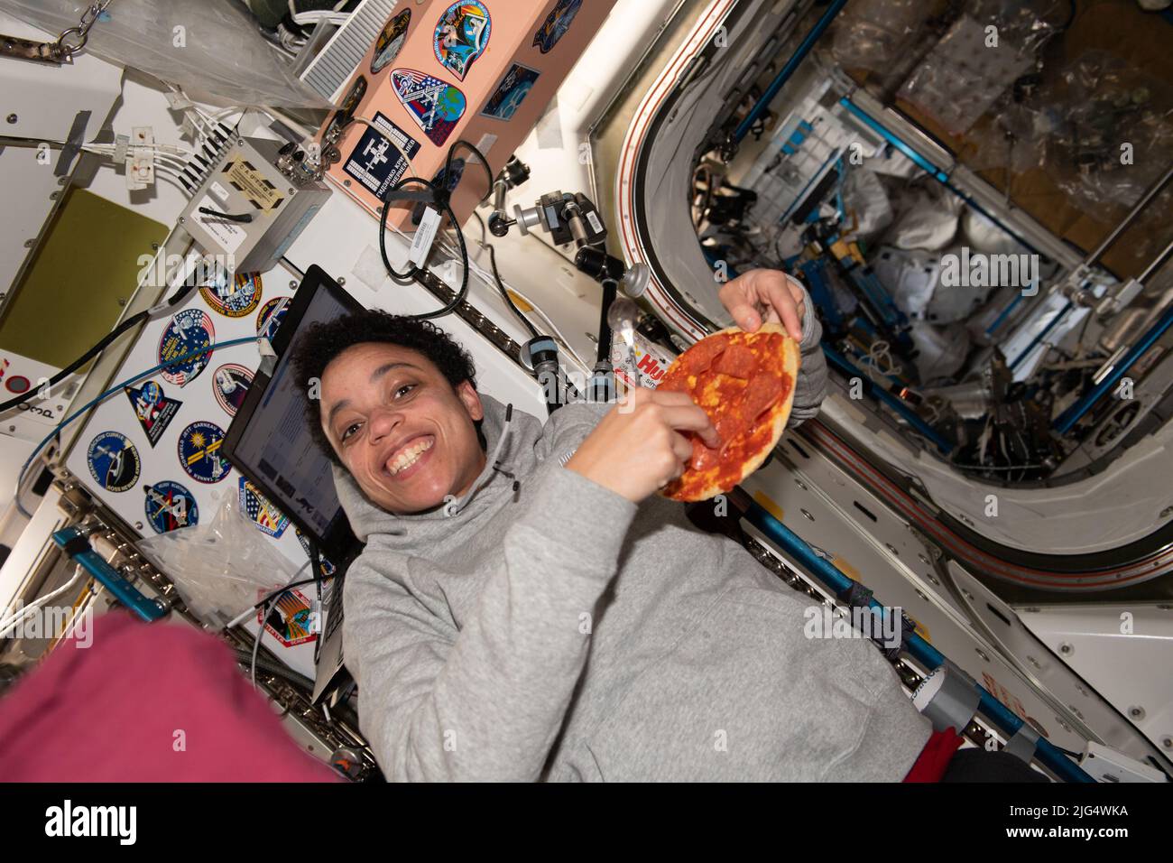 Jessica Watkins, ingeniera de vuelo de la Expedición 67 de la NASA, posa con su pizza de tamaño personal durante la cena a bordo de la Estación Espacial Internacional, el 27 de mayo de 2022 en órbita terrestre. Foto de stock