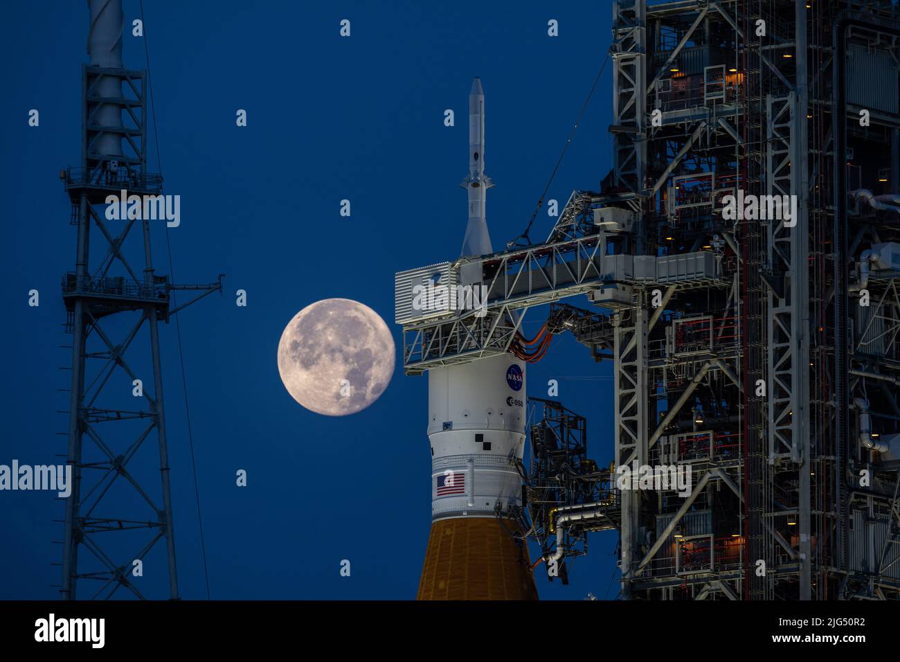 Una luna llena se eleva sobre el cohete del Sistema de Lanzamiento Espacial Artemis I de la NASA con la nave espacial Orion a bordo de un lanzador móvil en el Complejo de Lanzamiento 39B, en el Centro Espacial Kennedy, el 14 de junio de 2022, en Cabo Cañaveral, Florida. El SLS y Orion se están preparando para un ensayo de vestuario húmedo para practicar los plazos y procedimientos para el lanzamiento. Foto de stock