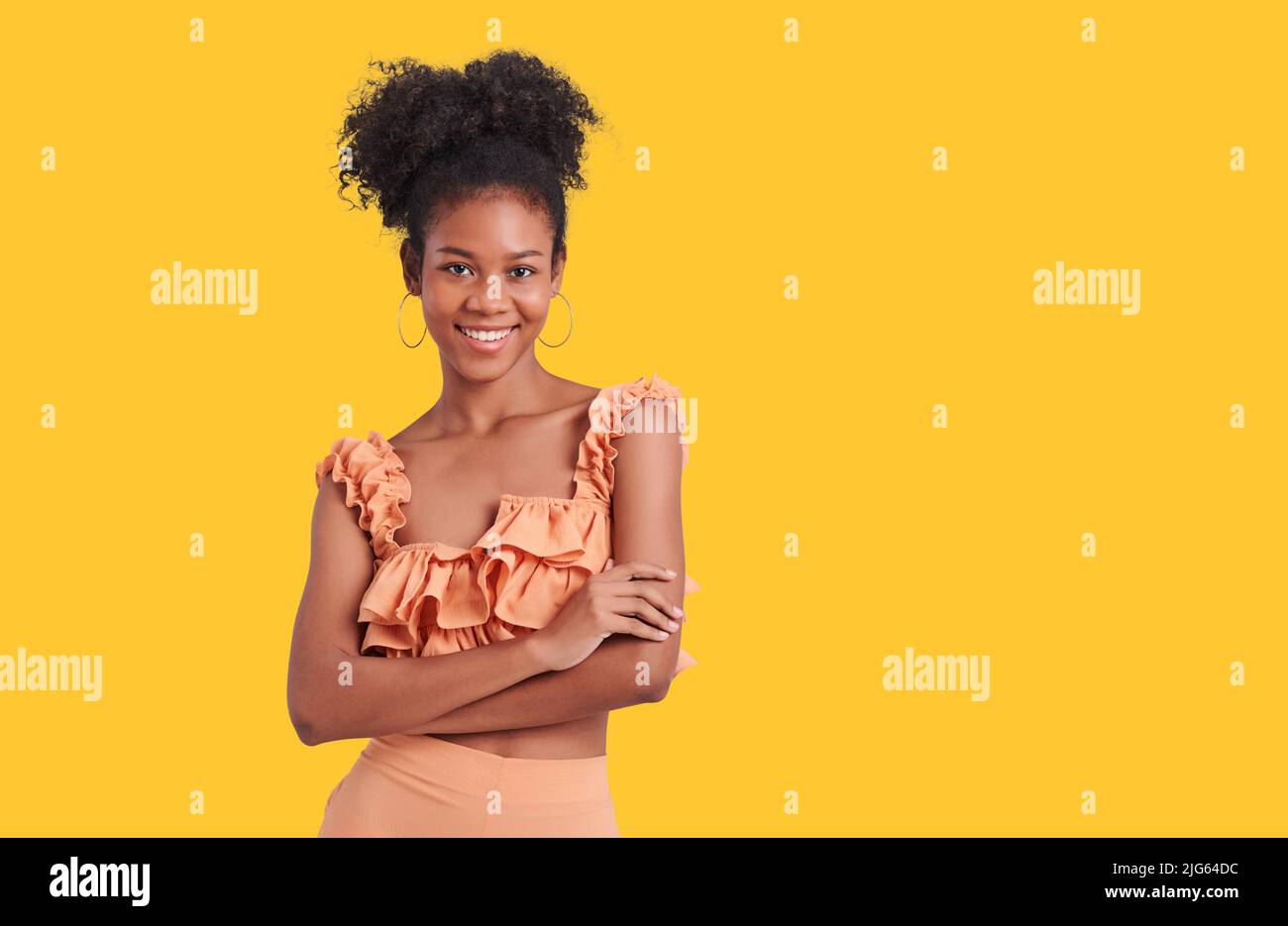 adorable encantadora mujer de piel oscura vestir naranja camisa vestido sonriendo aislado color amarillo fondo Foto de stock