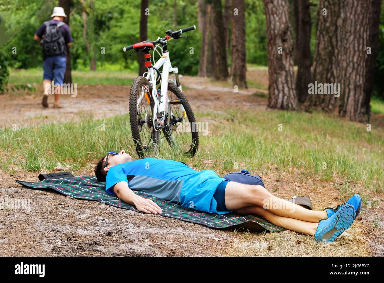 El ciclista con ropa deportiva descansa en un parque público en verano. Tiempo de descanso. Foto de stock