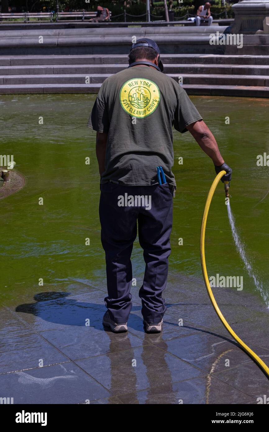 Un hombre del Cuerpo de Limpieza de la Ciudad de Nueva York limpia la fuente en Washington Square Park en Greenwich Village, Manhattan, Nueva York. Foto de stock