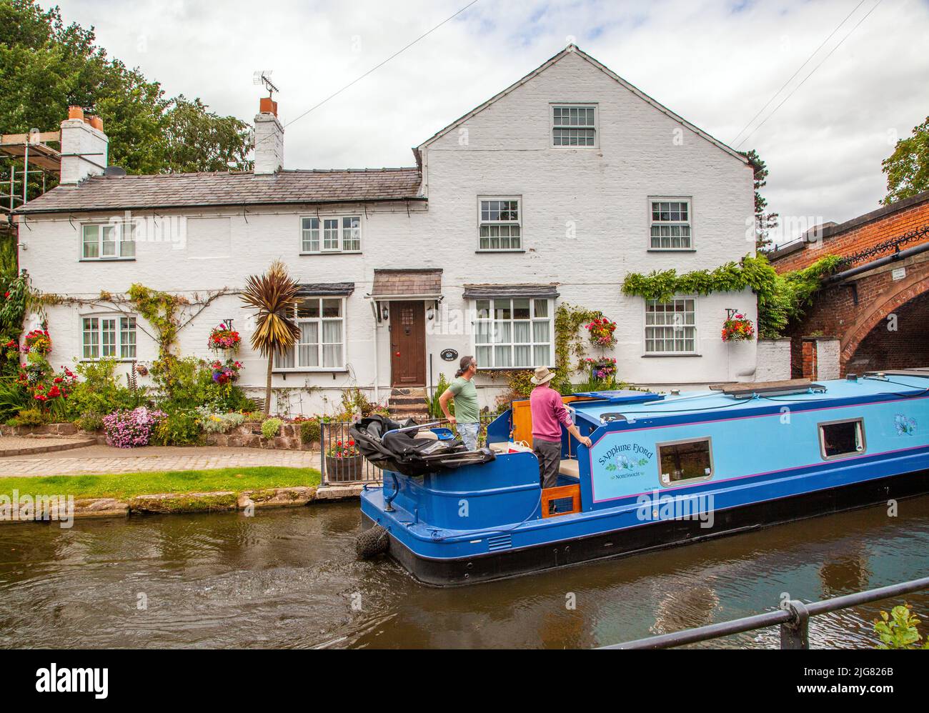 Canal narrowboat pasando por el pueblo de Cheshire de Lymm en el canal Bridgewater Foto de stock