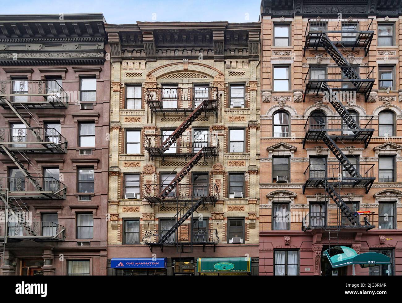 Fachada del antiguo edificio de apartamentos de Manhattan con escaleras externas para escaparse de incendios y tiendas en la planta baja Foto de stock