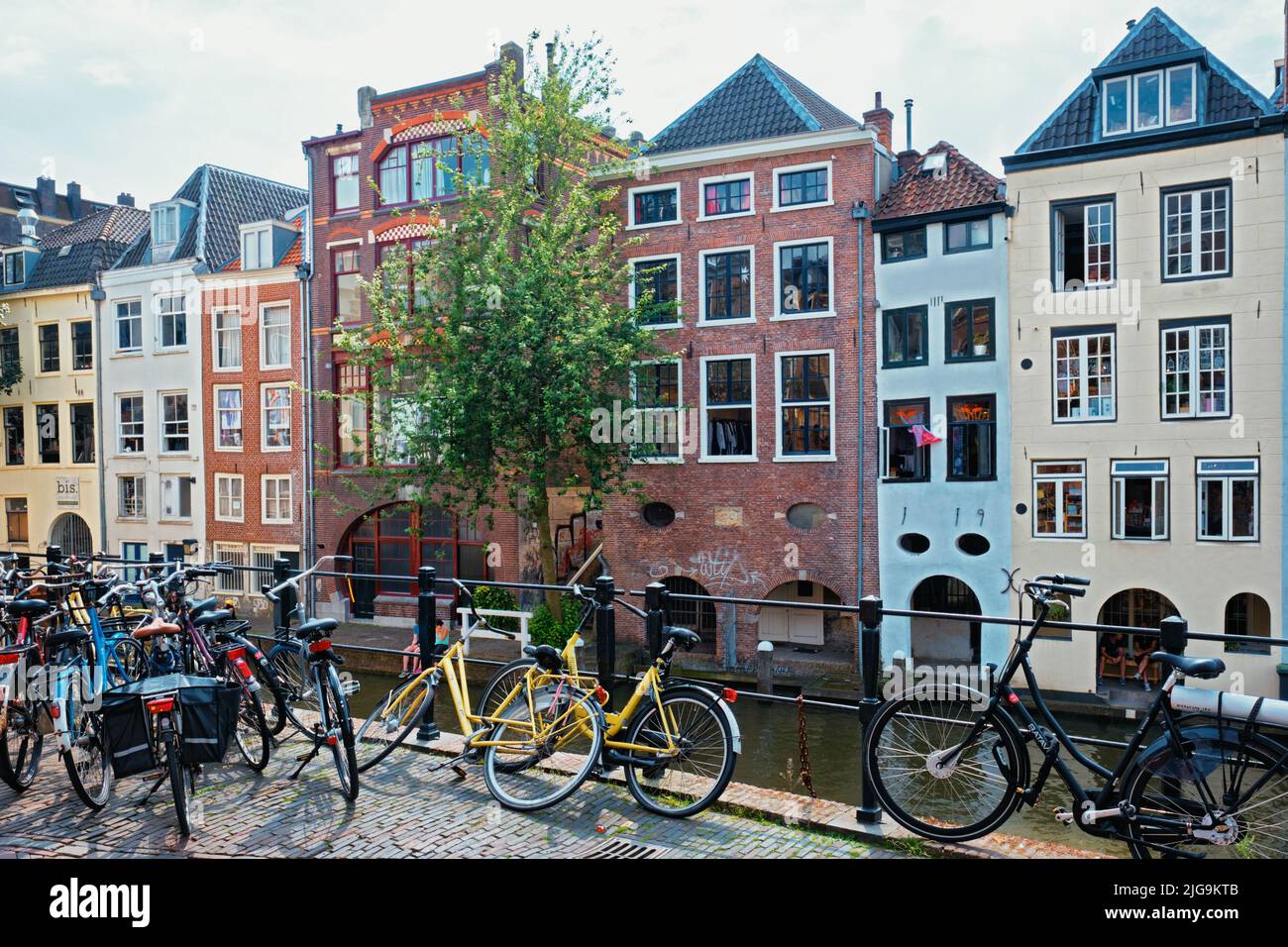 Bicicletas que son un transporte muy popular en los Países Bajos estacionado en la calle cerca de casas antiguas Foto de stock