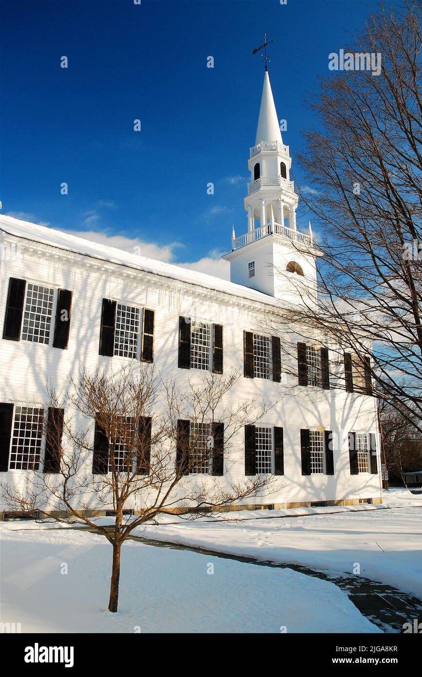 Una clásica iglesia de Nueva Inglaterra de torre blanca se encuentra en una escena campestre durante una nieve invernal que invoca una escena navideña Foto de stock
