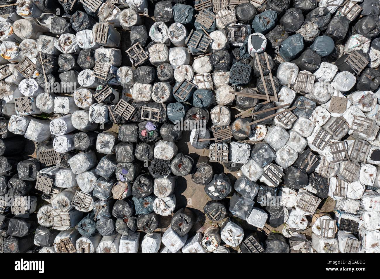 Almacenamiento ilegal de residuos domésticos sólidos, botellas de plástico y bolsas de basura. Contaminación del suelo. Vista superior de la antena. Foto de stock