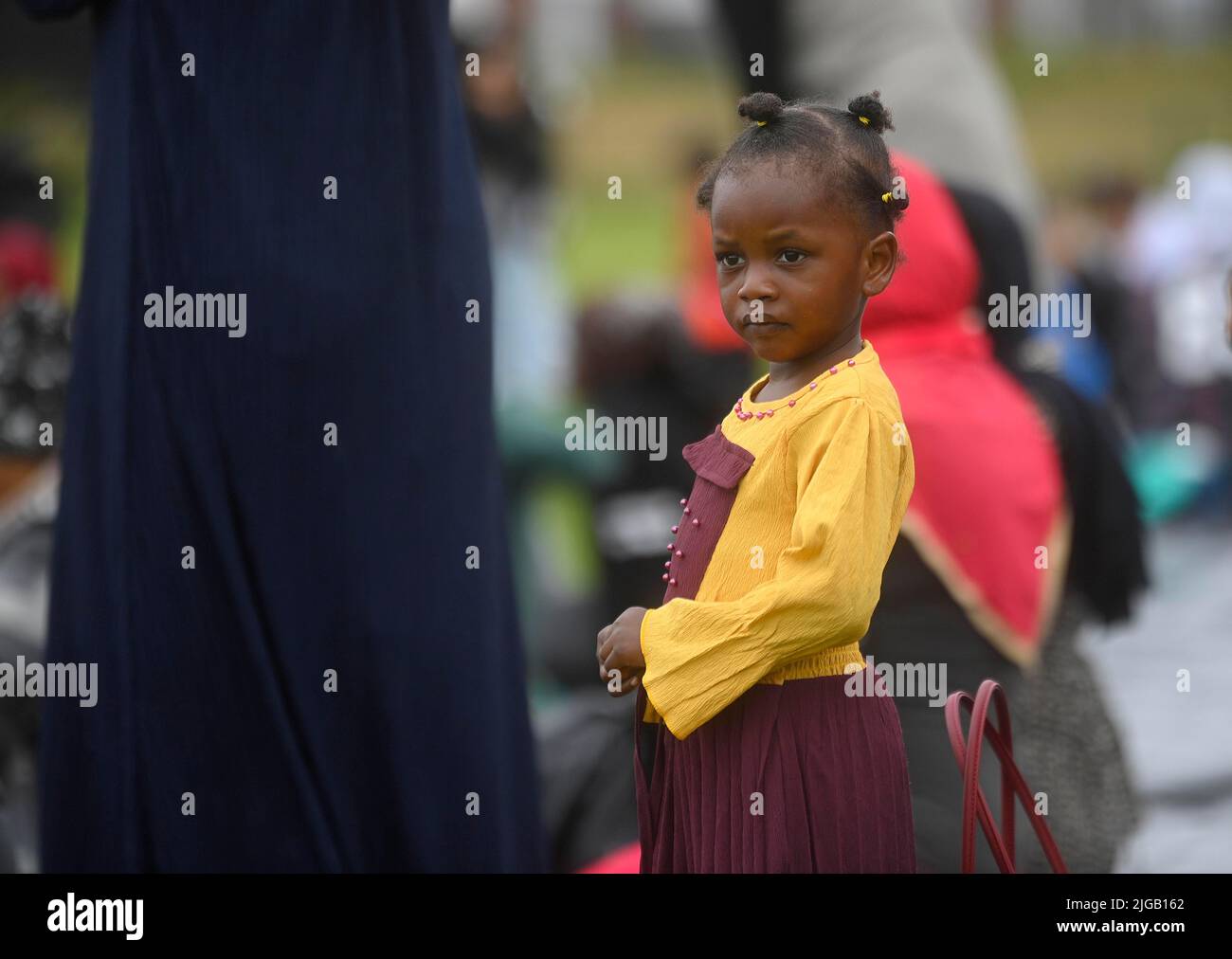 Un niño mira a la multitud durante el festival Eid en los terrenos de Davitt Park GAA en Belfast. El festival Eid es un día importante en el calendario musulmán cuando la comida se comparte con parientes, amigos y pobres. Fecha de la foto: Sábado 9 de julio de 2022. Foto de stock