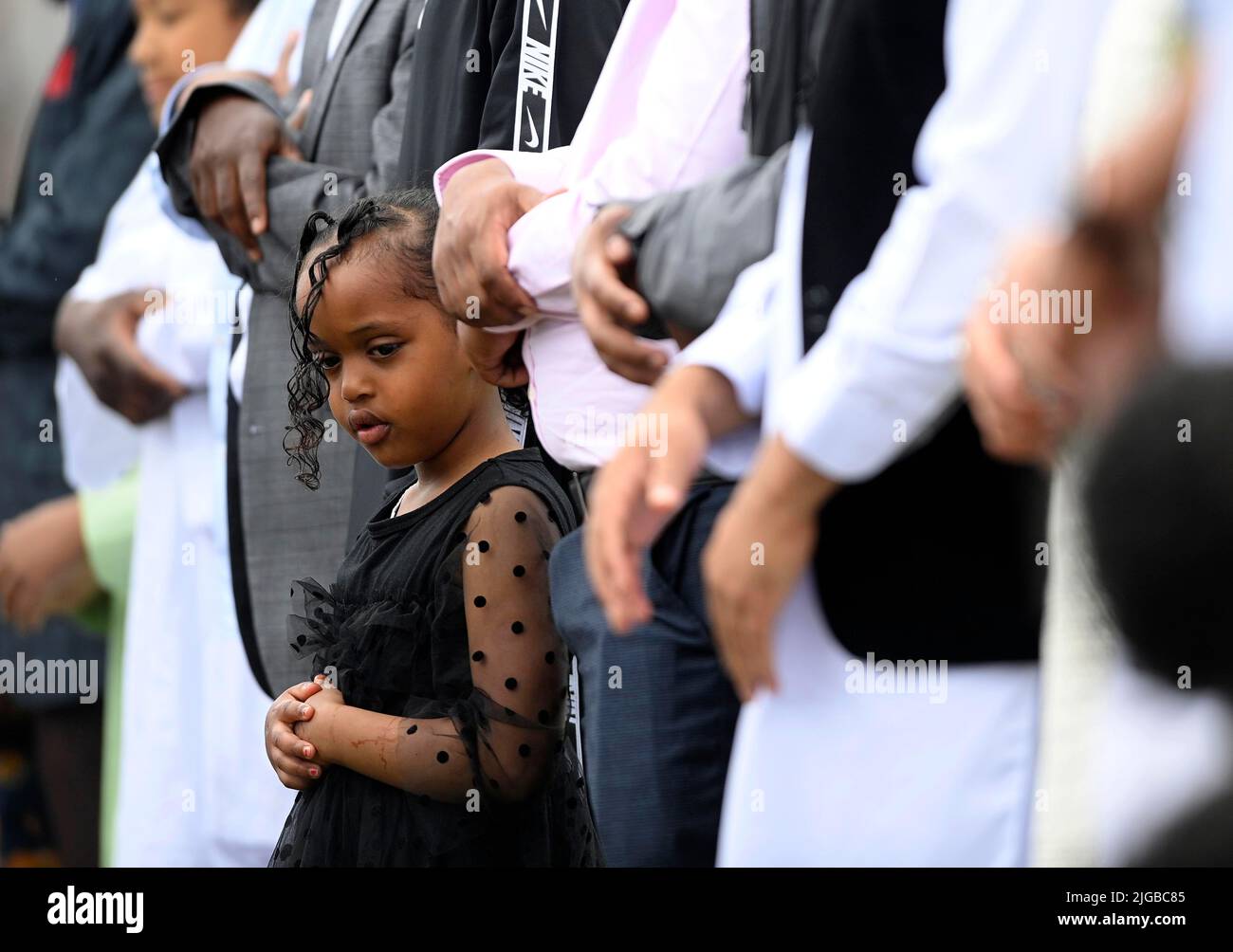 Un niño mira mientras se rezan durante el festival Eid en los terrenos de Davitt Park GAA en Belfast. El festival Eid es un día importante en el calendario musulmán cuando la comida se comparte con parientes, amigos y pobres. Fecha de la foto: Sábado 9 de julio de 2022. Foto de stock