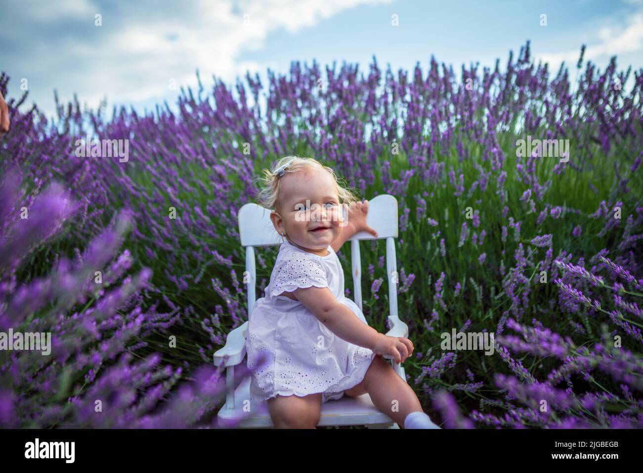 Sonriendo niña linda en un campo de lavanda al atardecer. Foto de stock