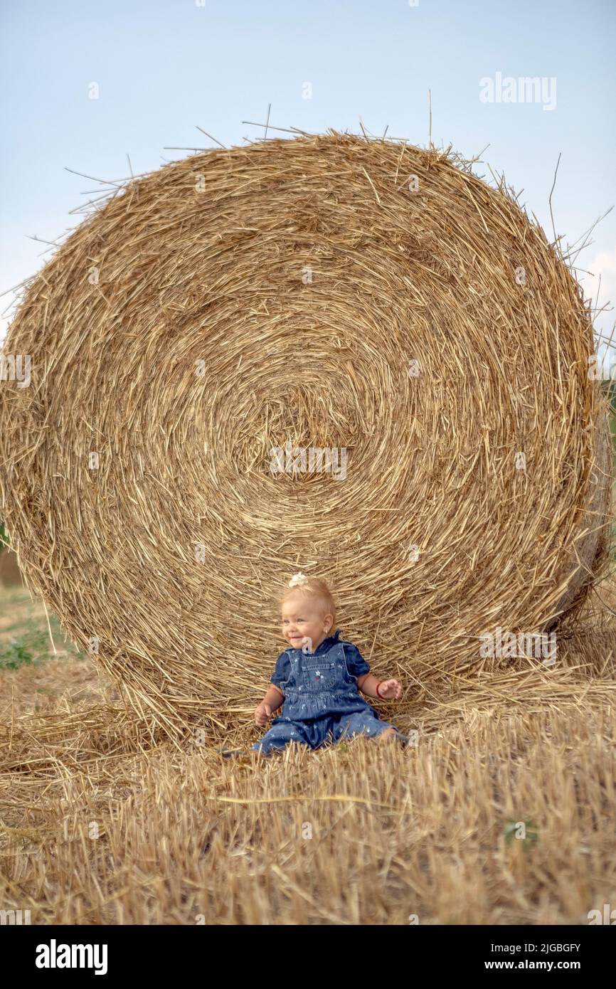 Pequeña chica en el campo de trigo.Pequeña chica sonriendo y feliz. Naturaleza en el país Foto de stock