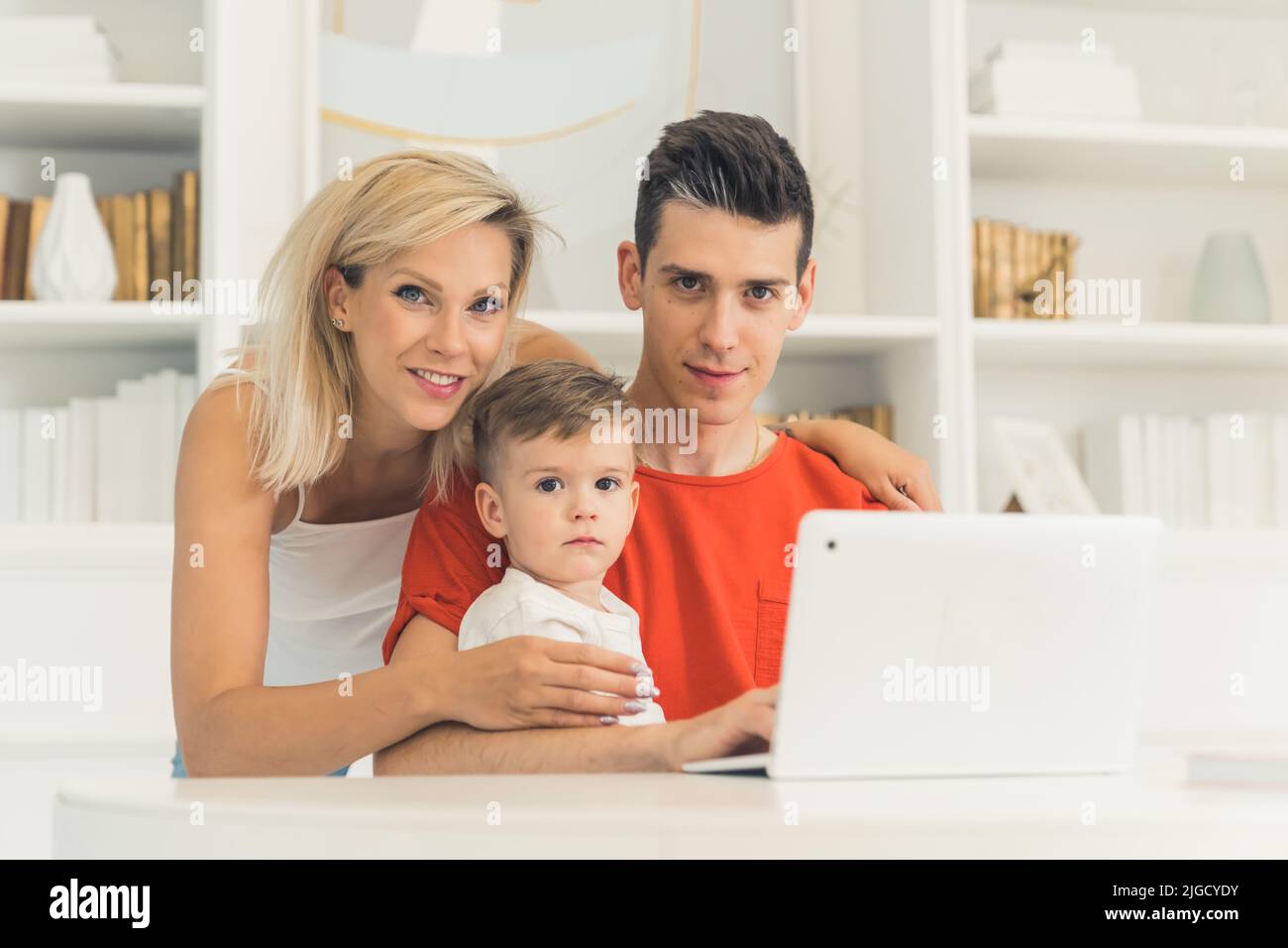Joven pareja caucásica sentada frente al portátil en casa, primer plano medio, concepto de familia y tecnología. Fotografía de alta calidad Foto de stock