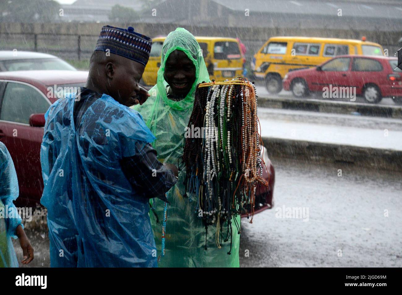 Lagos, Nigeria, 9th Julio, 2022 Vendedor de cuentas de oración discute con un comprador como fiel musulmán, a pesar de las fuertes lluvias, oren para conmemorar el festival Eid-el-Kabir 2022 en Ikeja, a lo largo de Lagos, Nigeria, el sábado 9 de julio de 2022. Foto de Adekunle Ajayi Crédito: Adekunle Ajayi/Alamy Live News Foto de stock