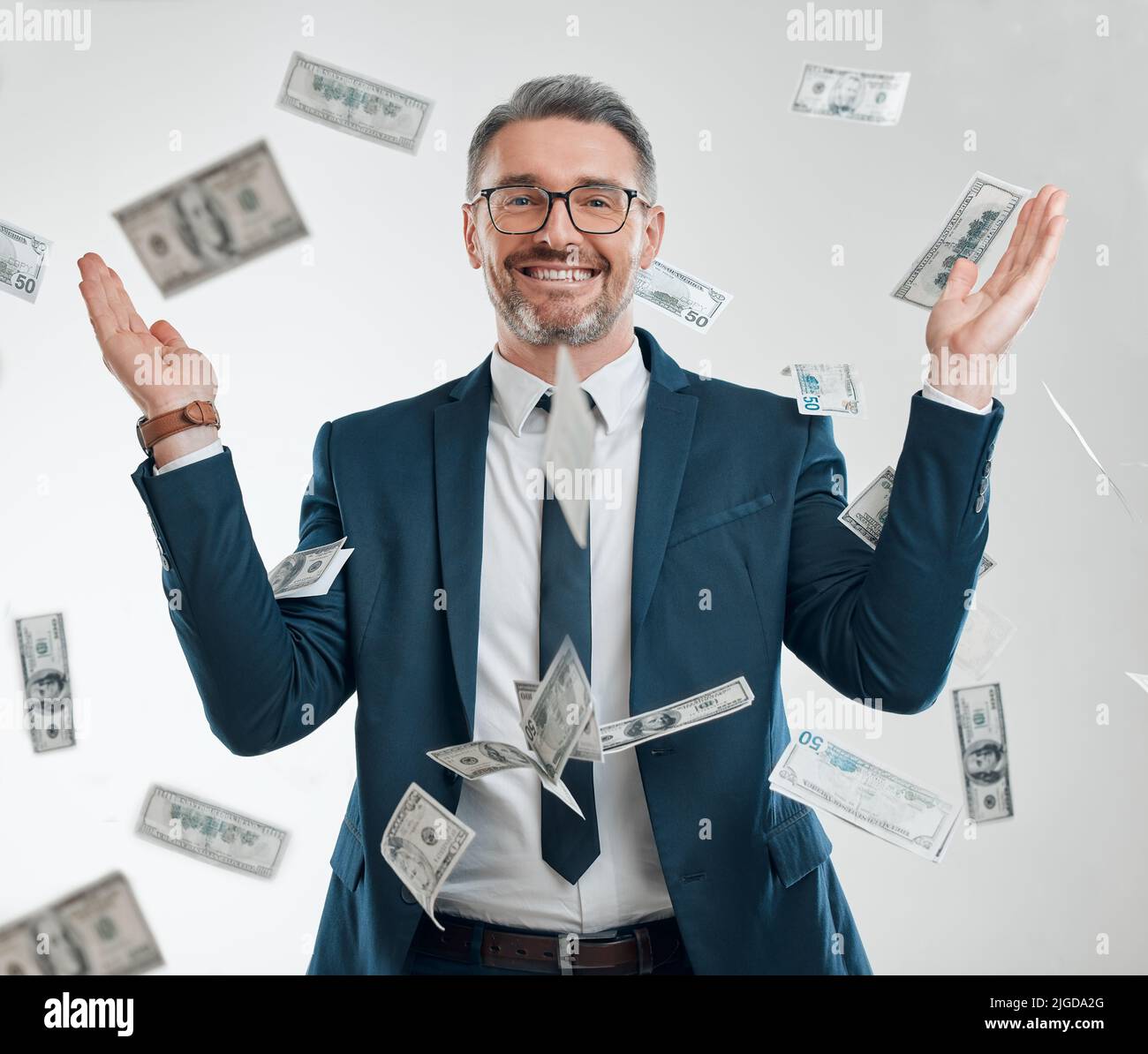 Parece que él golpeó el jackpot. Retrato de estudio de un hombre de negocios maduro rodeado de caída de dinero. Foto de stock