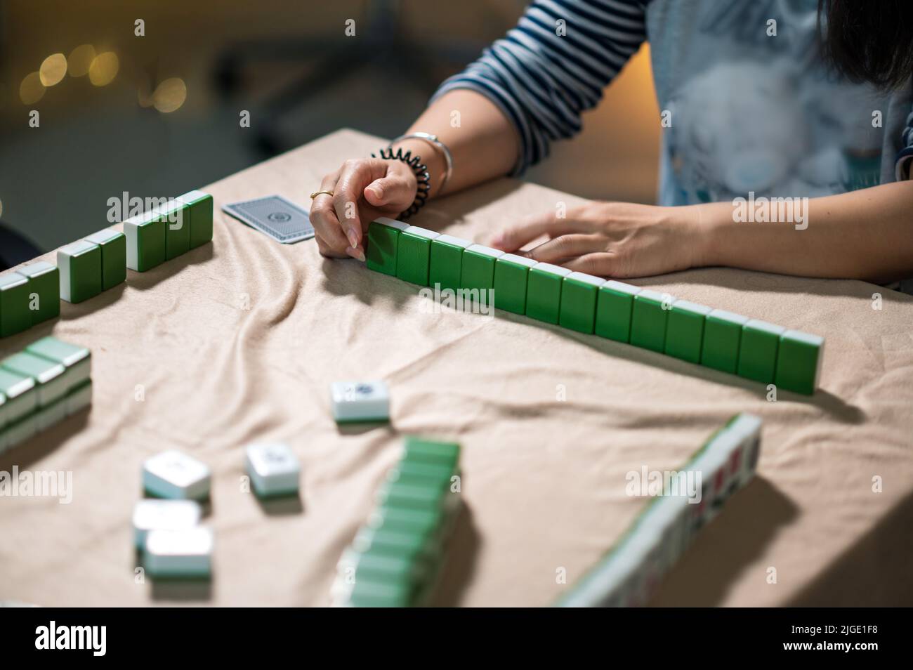 Amigas jugando mahjong tradicional chino juego de mesa en casa. Traducción: El texto de las fichas muestra los caracteres chinos para los números del 1 al 9 y si Foto de stock