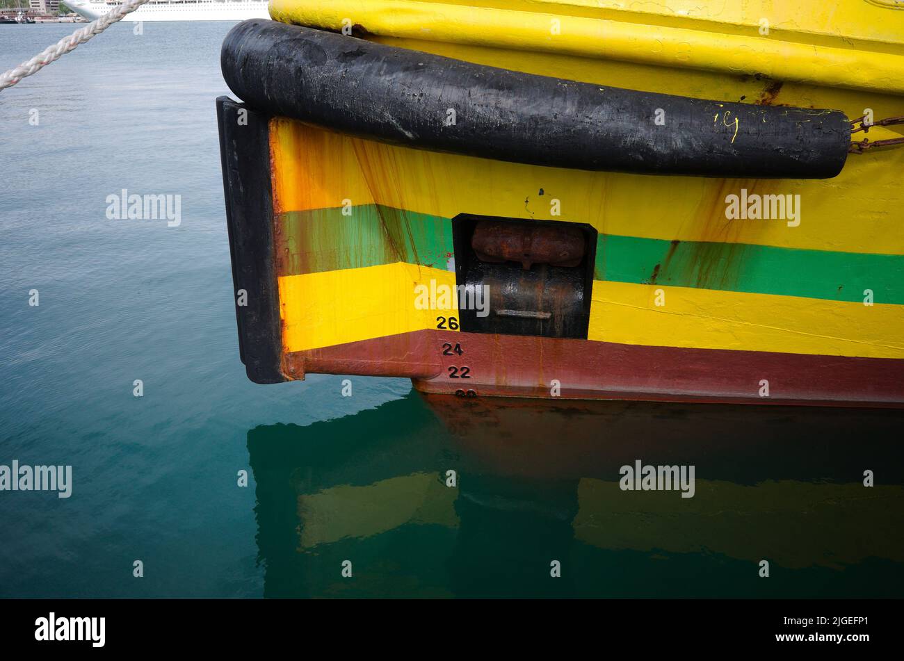 Arco de barco amarillo con línea de flotación, cable de plomo, ancla elevada, guardabarros de goma y marcas de tiro en el arco del barco. Proa de barco de barco de pesca de primer plano Foto de stock