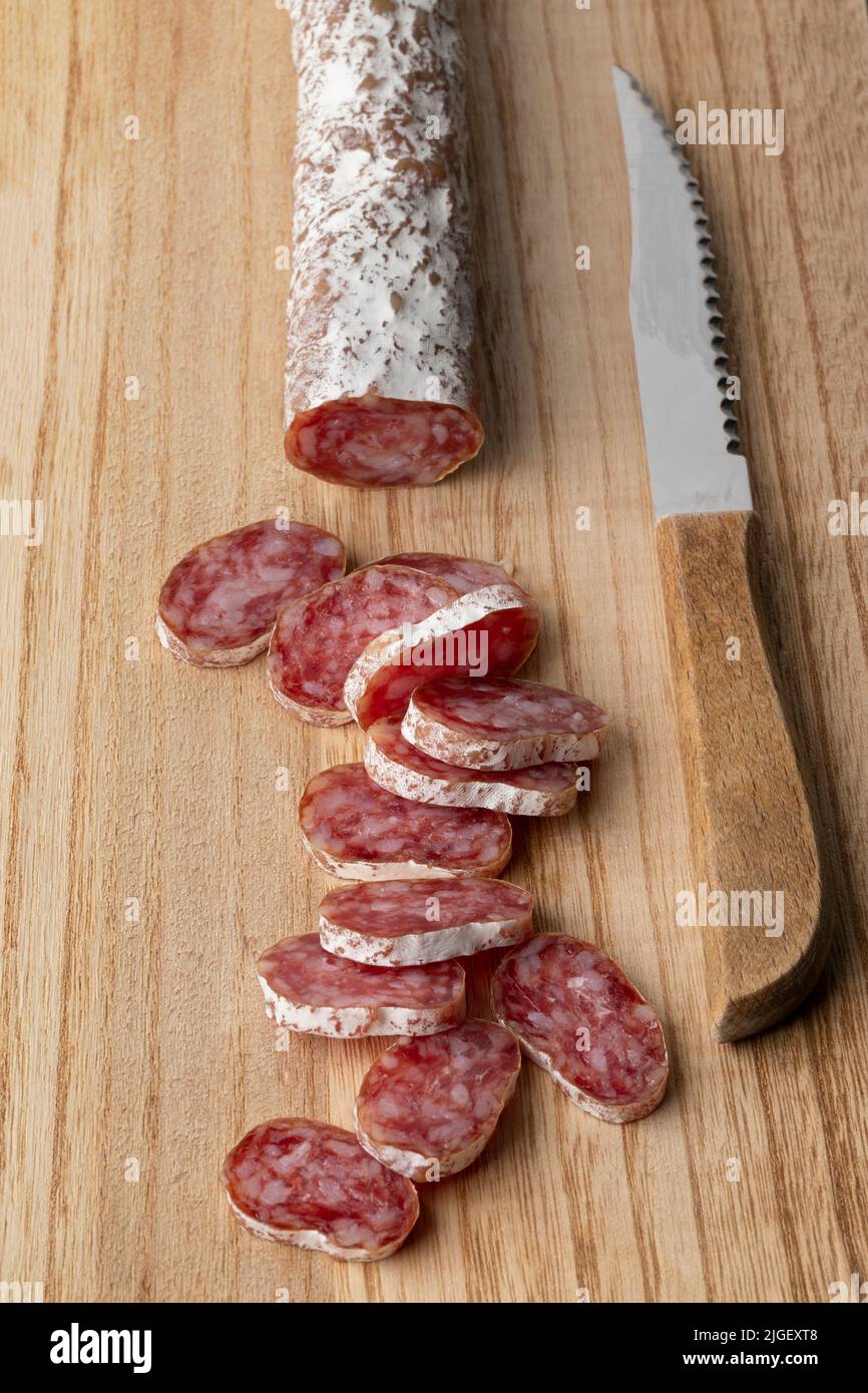 Salchicha catalana tradicional, fuet, y rebanadas en una tabla de cortar de cerca Foto de stock