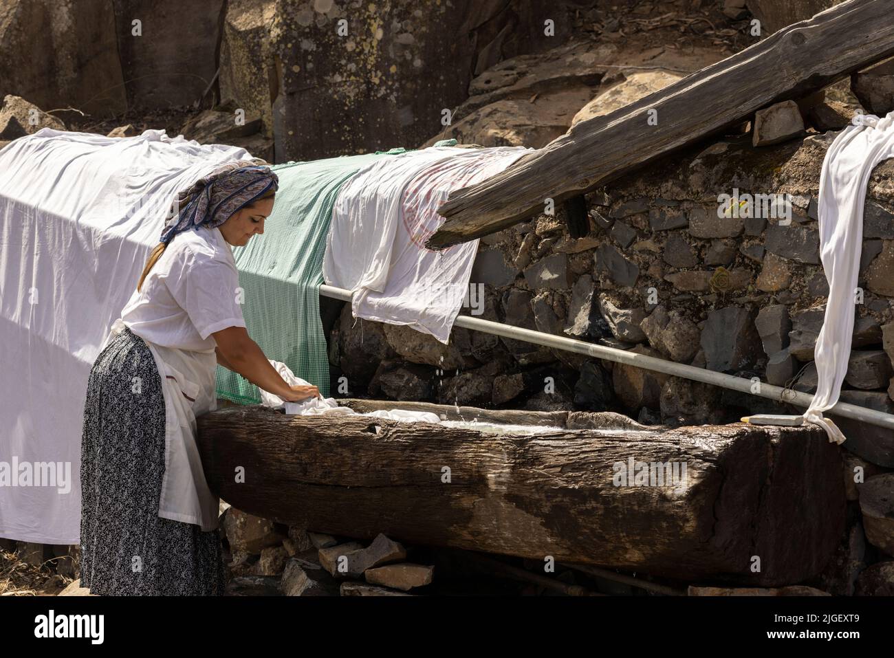 Chirche, Tenerife, 10 de julio de 2022. Niñas lavando la ropa en una canaleta de madera en el lugar de lavado comunal. Los aldeanos celebran el Día de tradiciones, Día de las Tradiciones en el pequeño pueblo de montaña donde renactan escenas del estilo de vida rural vivido por sus antepasados en la década de 1940s Foto de stock