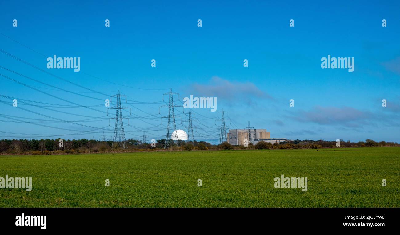 Las centrales nucleares de Sizewell se encuentran a gran distancia, con campos verdes en primer plano y muchas líneas de energía Foto de stock