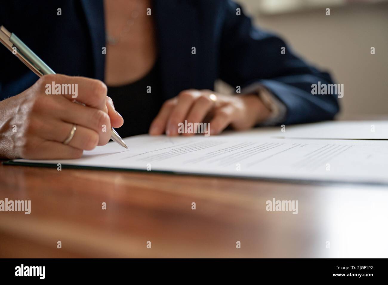 Vista de primer plano de ángulo bajo de una mujer de negocios que firma un documento o contrato. Foto de stock