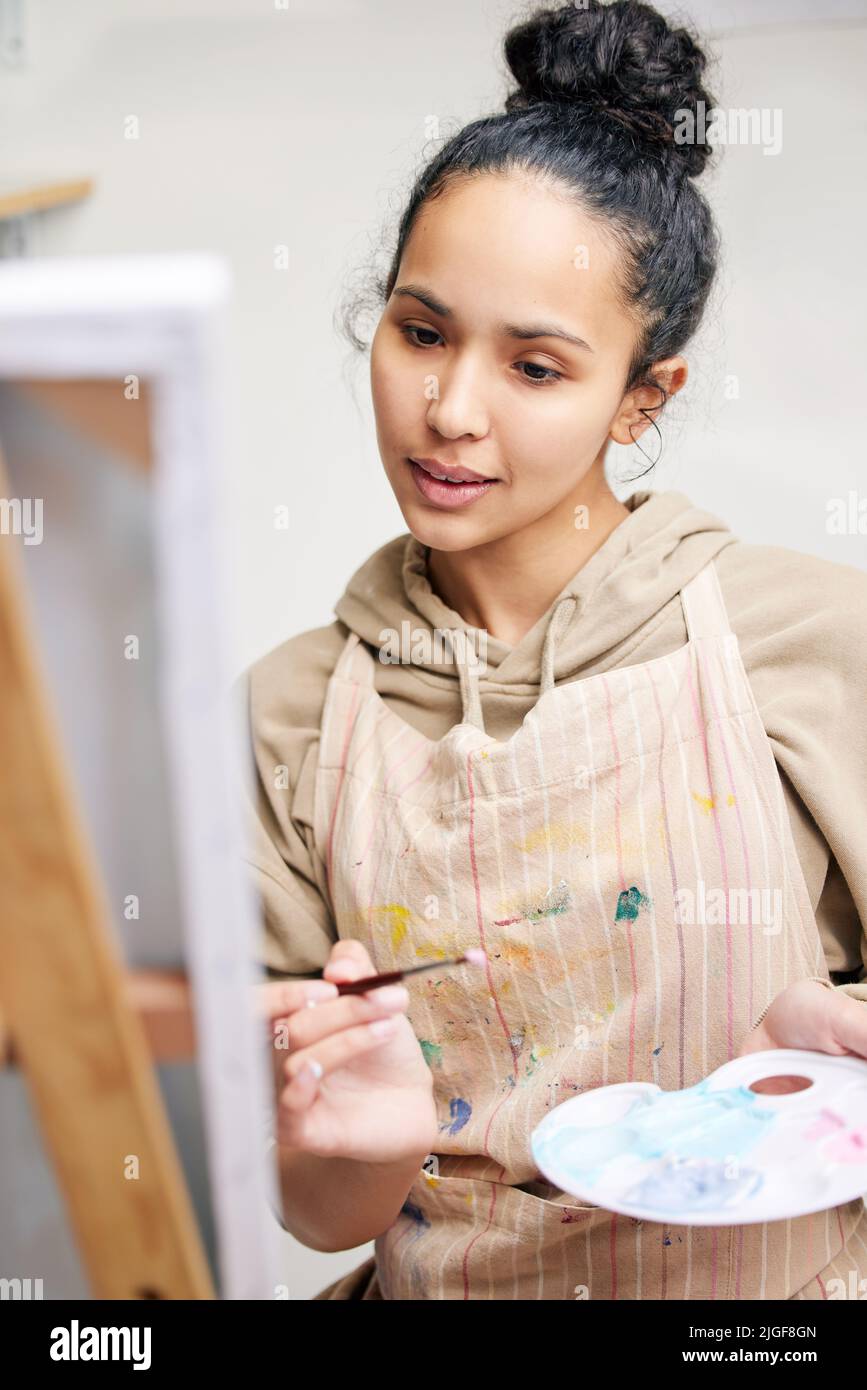 La pintura trae su paz. Plano de ángulo bajo de una atractiva mujer joven pintando sobre un lienzo en su estudio. Foto de stock