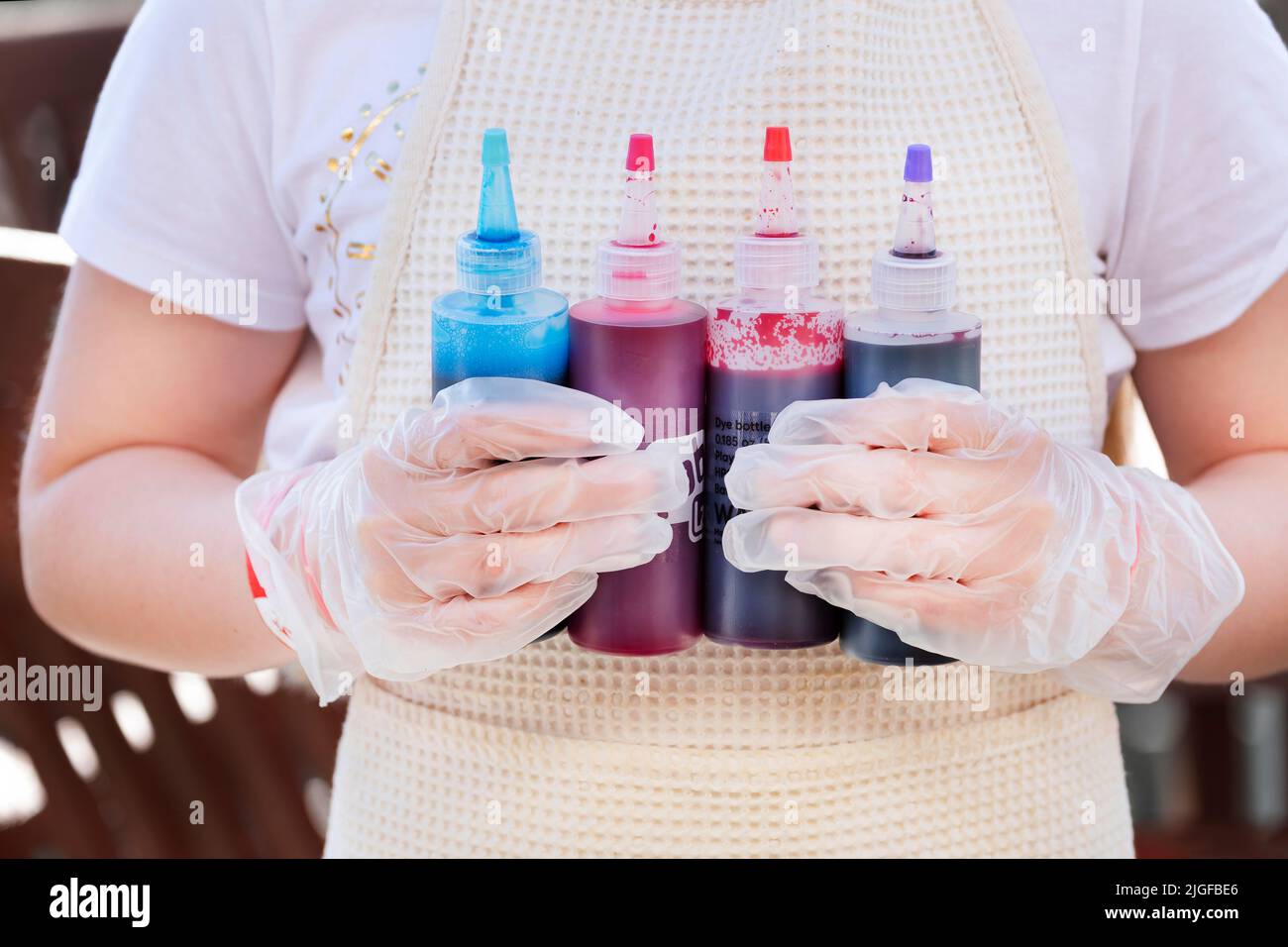 Un niño aplica un tinte de ropa a una camiseta blanca mojada atada. Esta técnica de teñido de corbata crea un efecto de espiral una vez que el tinte se ha secado en la tela Foto de stock