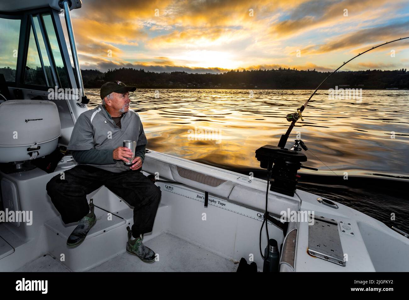 WA20627-00....WASHINGTON - Phil Russell mira su caña de pescar para una huelga mientras que trolling para el salmón en el sonido de Puget. MR R8 Foto de stock