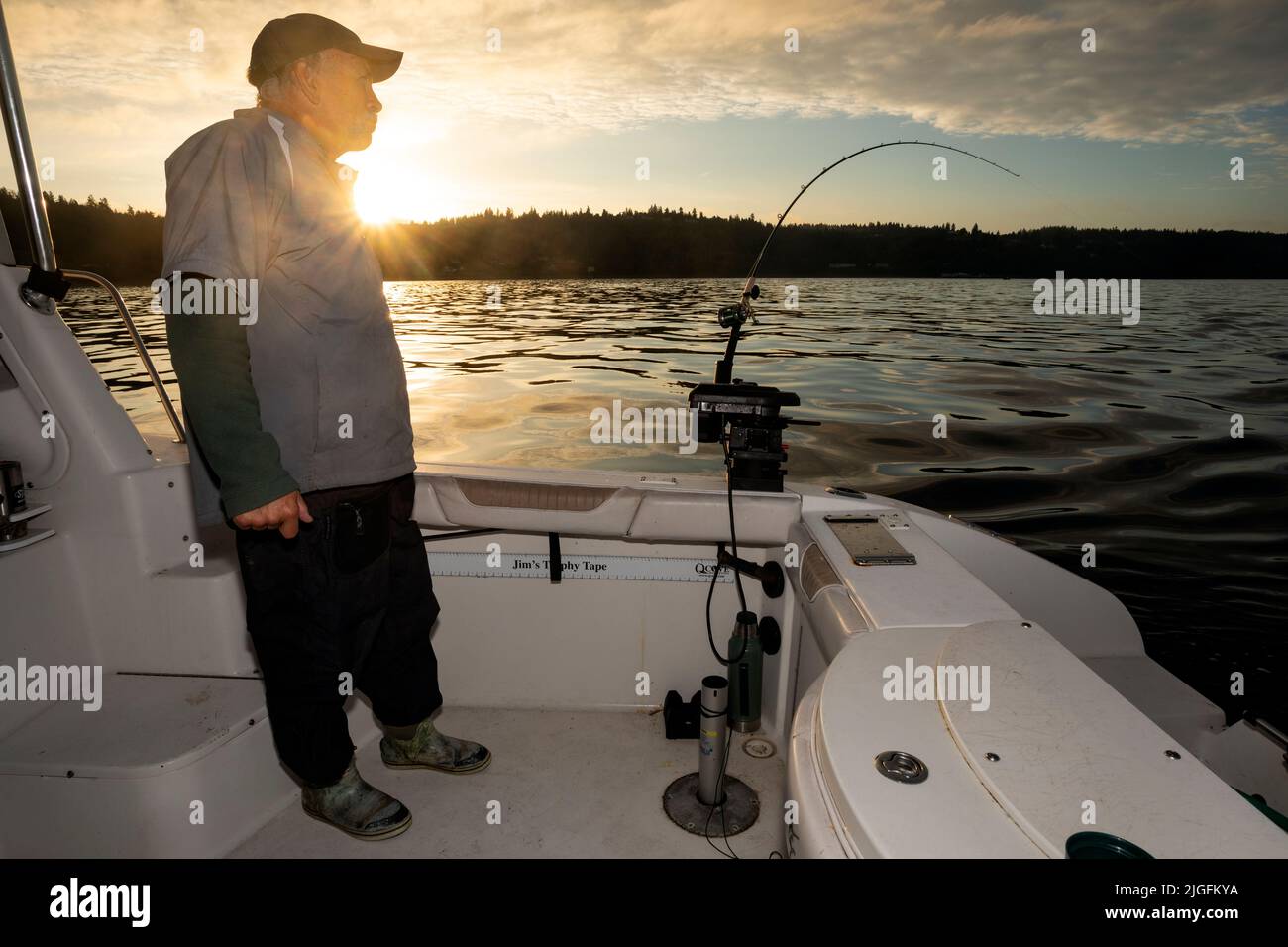 WA20628-00....WASHINGTON - Phil Russell mira su caña de pescar para una huelga mientras que trolling para el salmón en el sonido de Puget. MR R8 Foto de stock