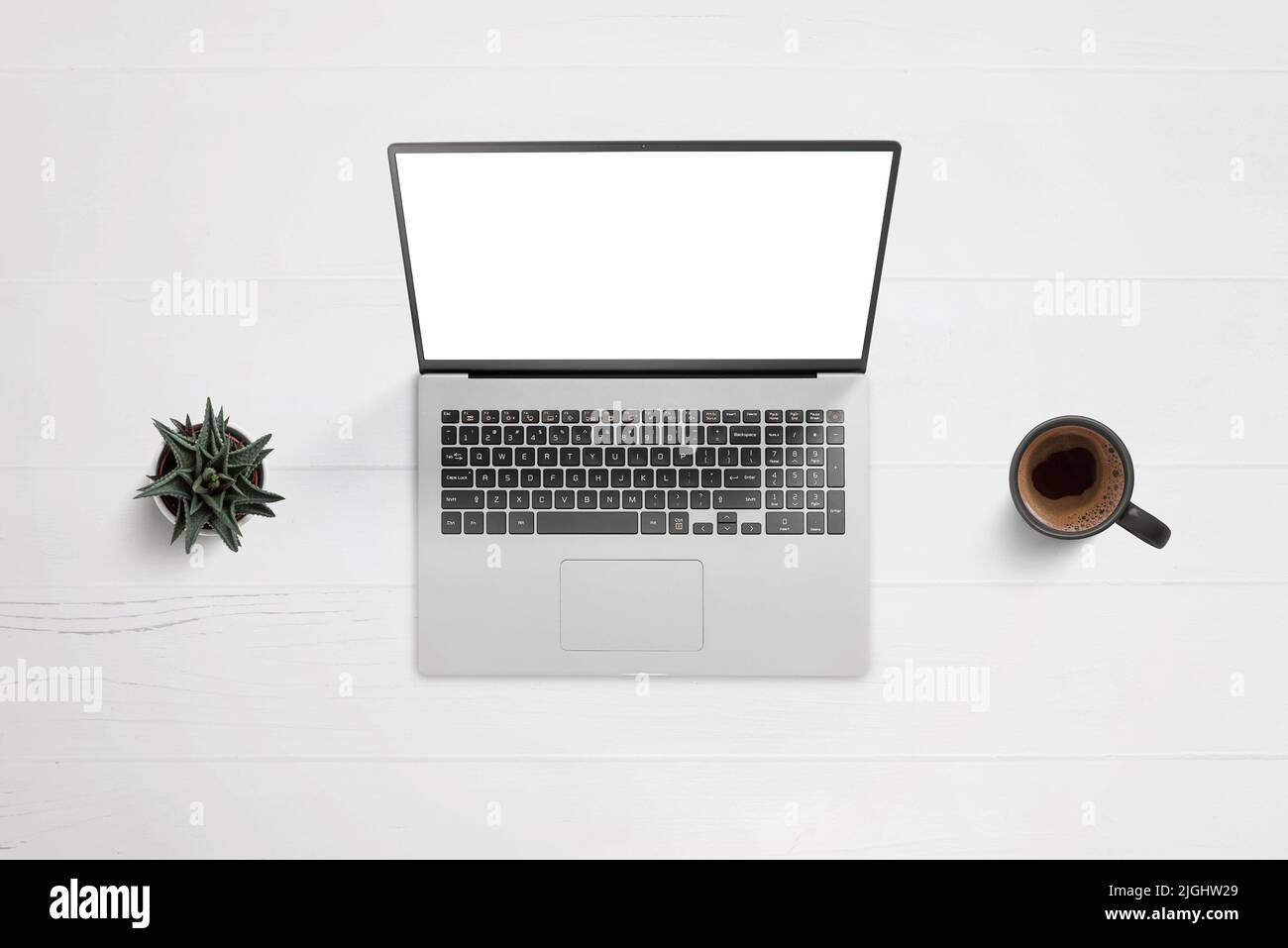 Ordenador portátil en el escritorio con pantalla aislada para aplicaciones o presentaciones de diseño de páginas web. Vista superior, composición plana con planta y taza de café al lado Foto de stock