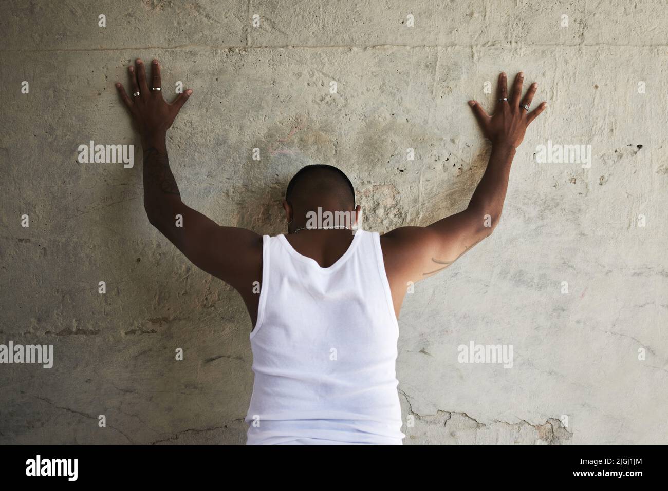 Manos arriba y separar em. Foto trasera de un hombre apoyado contra una  pared urbana con las manos levantadas Fotografía de stock - Alamy