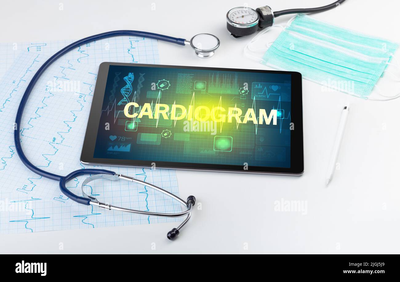 Tableta pc y material médico con inscripción DE ELECTROCARDIOGRAMA, concepto de prevención Foto de stock