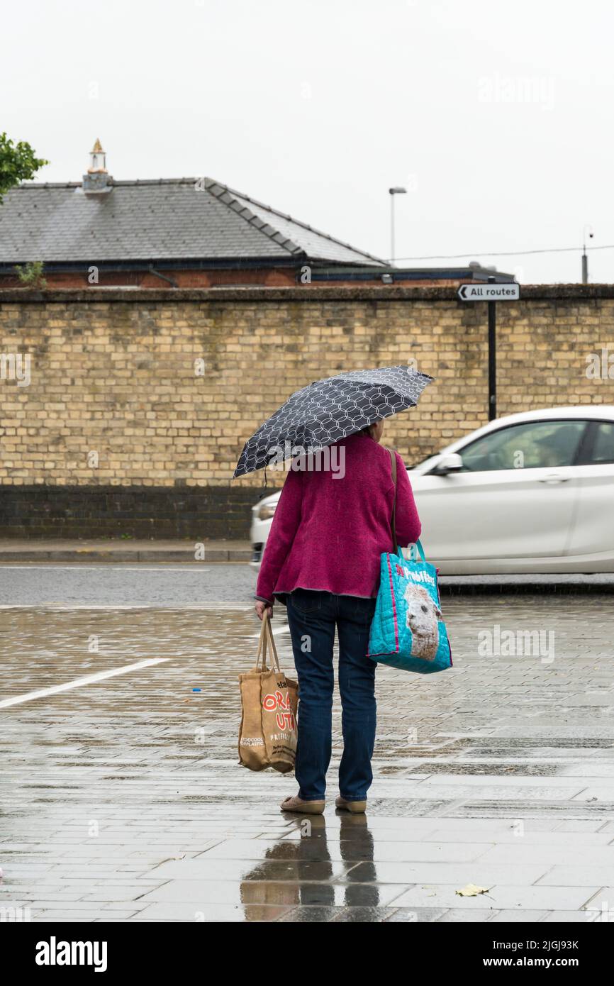 Señora llevando paraguas abierto en el downpour St Marys Street Lincoln 2022 Foto de stock