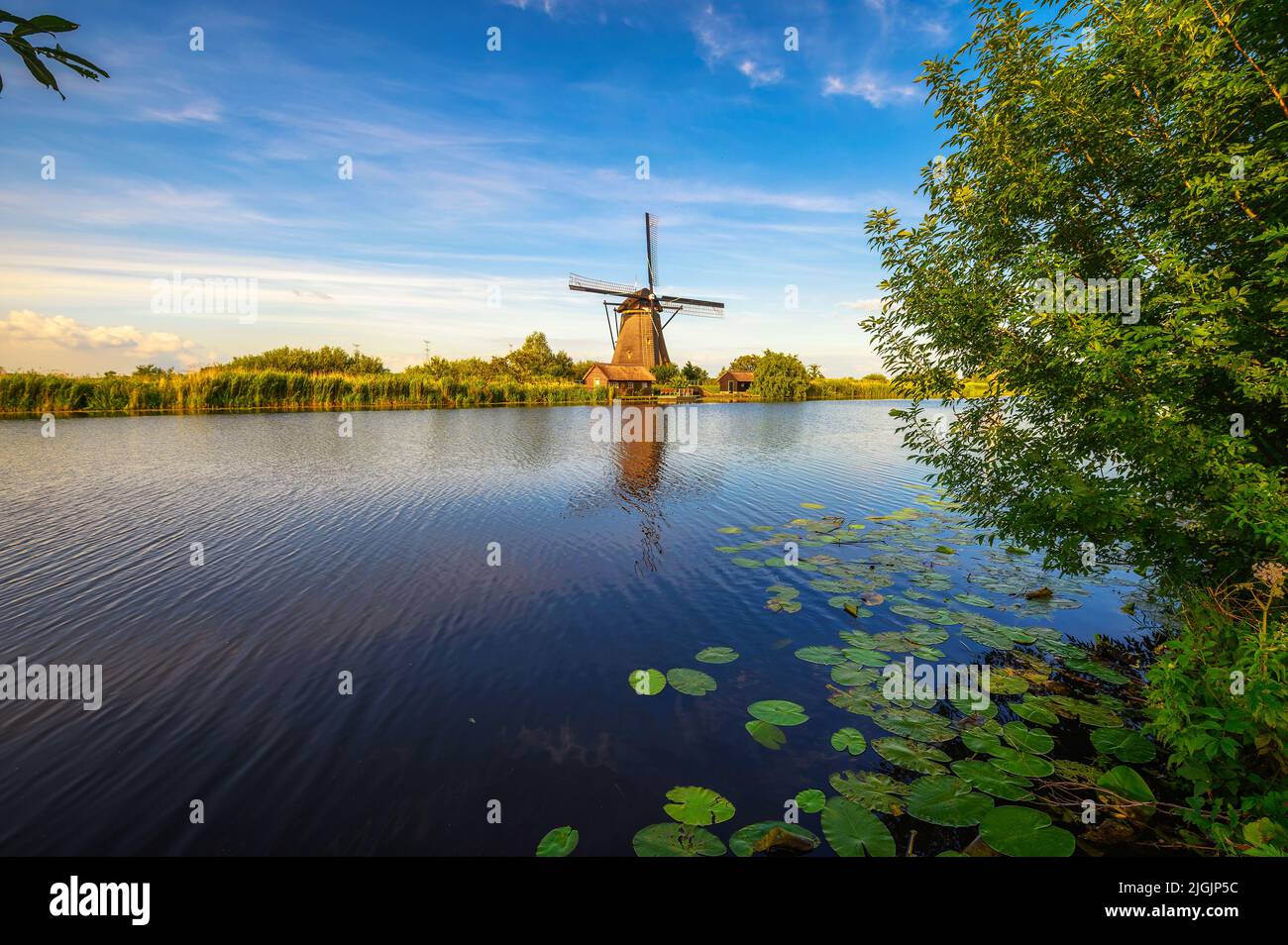 Histórico molino de viento y un río que fluye en Kinderdijk, Países Bajos Foto de stock