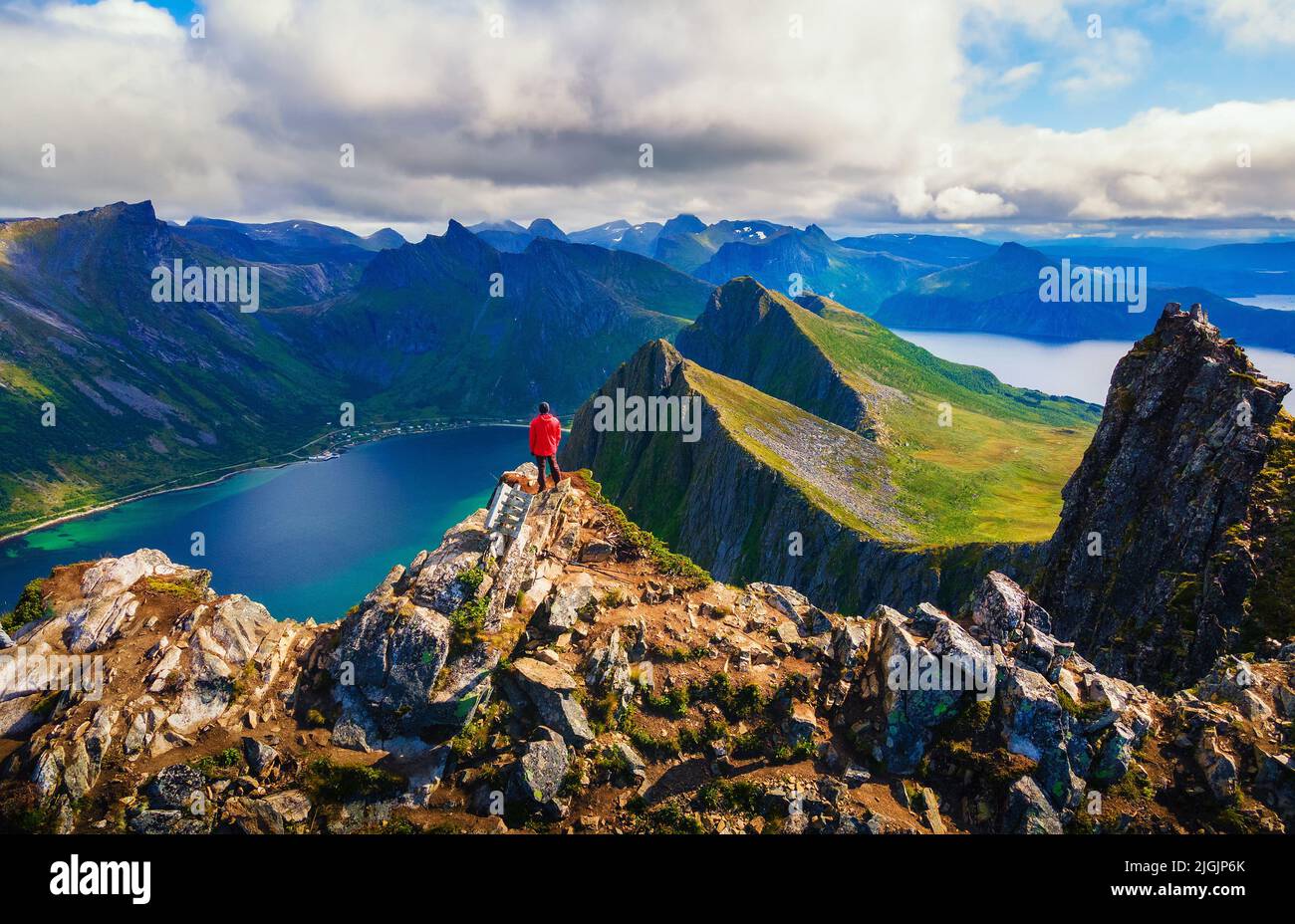Excursionista de pie en la cima de la montaña Husfjellet en la isla Senja en Noruega Foto de stock