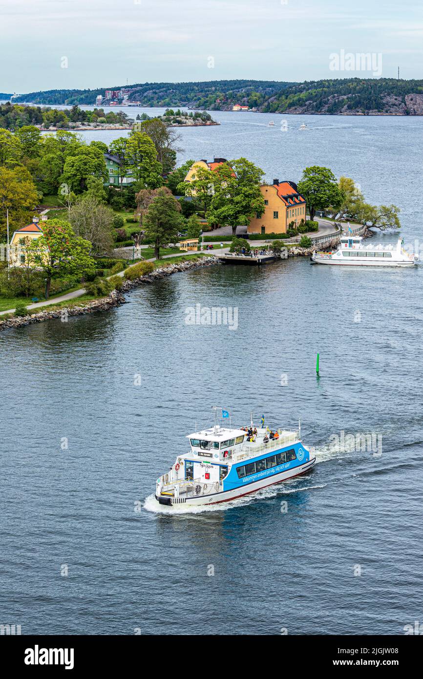 El barco de pasajeros 'Szovagen' pasa por el ferry en Blockhusudden en la isla de Djurgården en el archipiélago de Estocolmo, Suecia Foto de stock