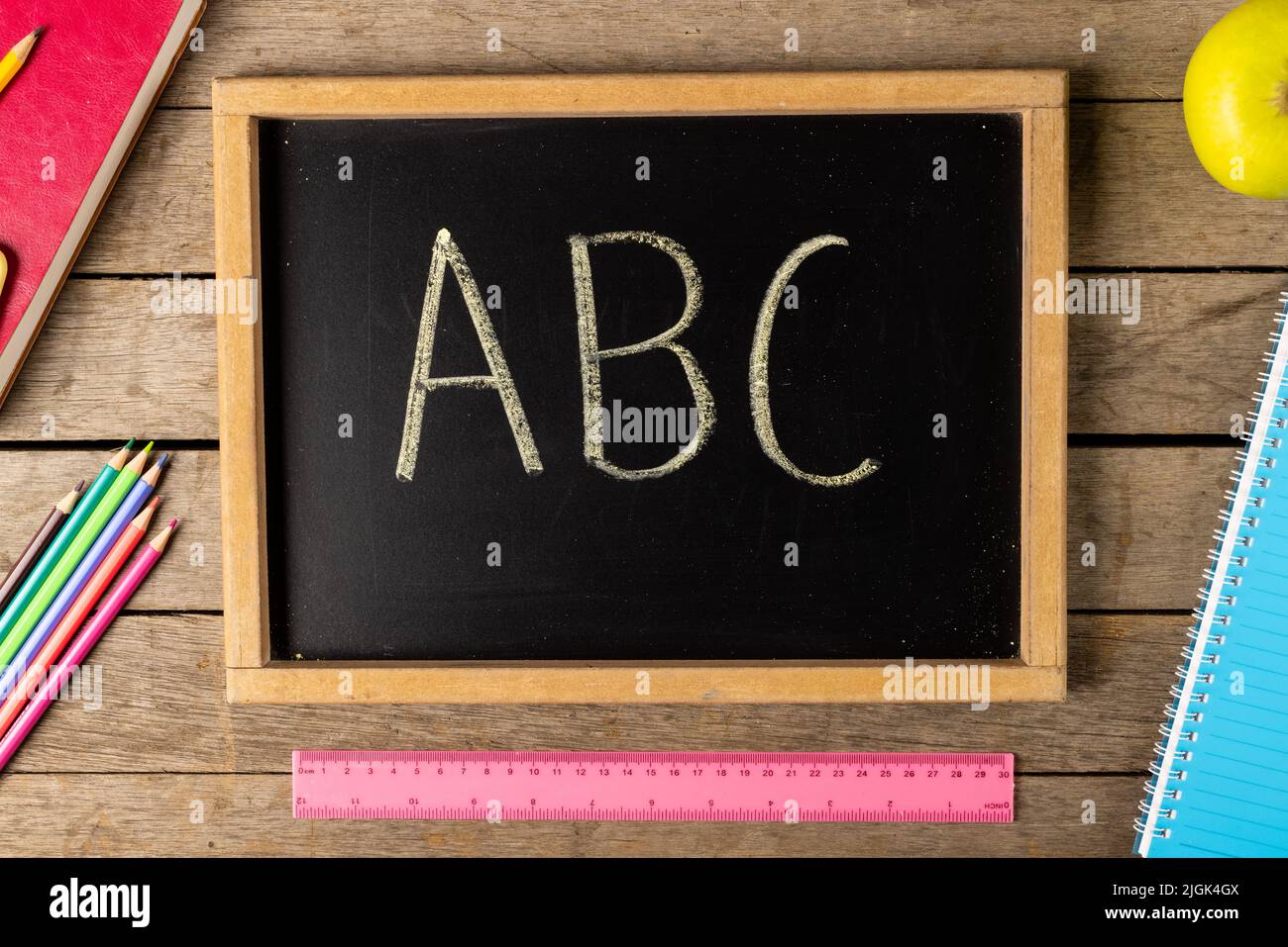 Composición de pizarra con abc y elementos escolares sobre fondo de madera  Fotografía de stock - Alamy