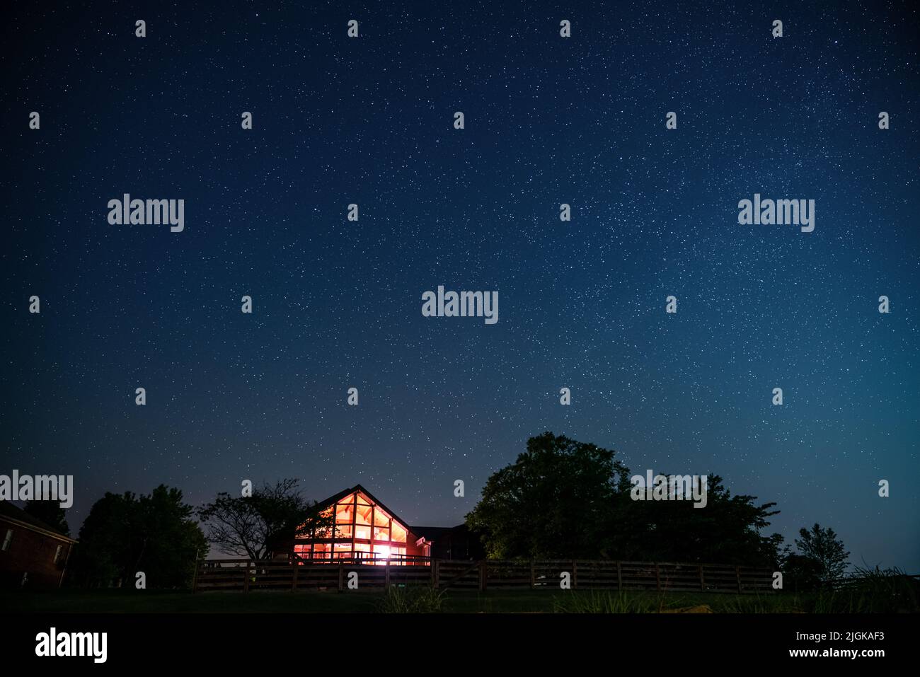 Vista del cielo nocturno y de la Vía Láctea con una casa en la zona rural de Kentucky en primer plano Foto de stock