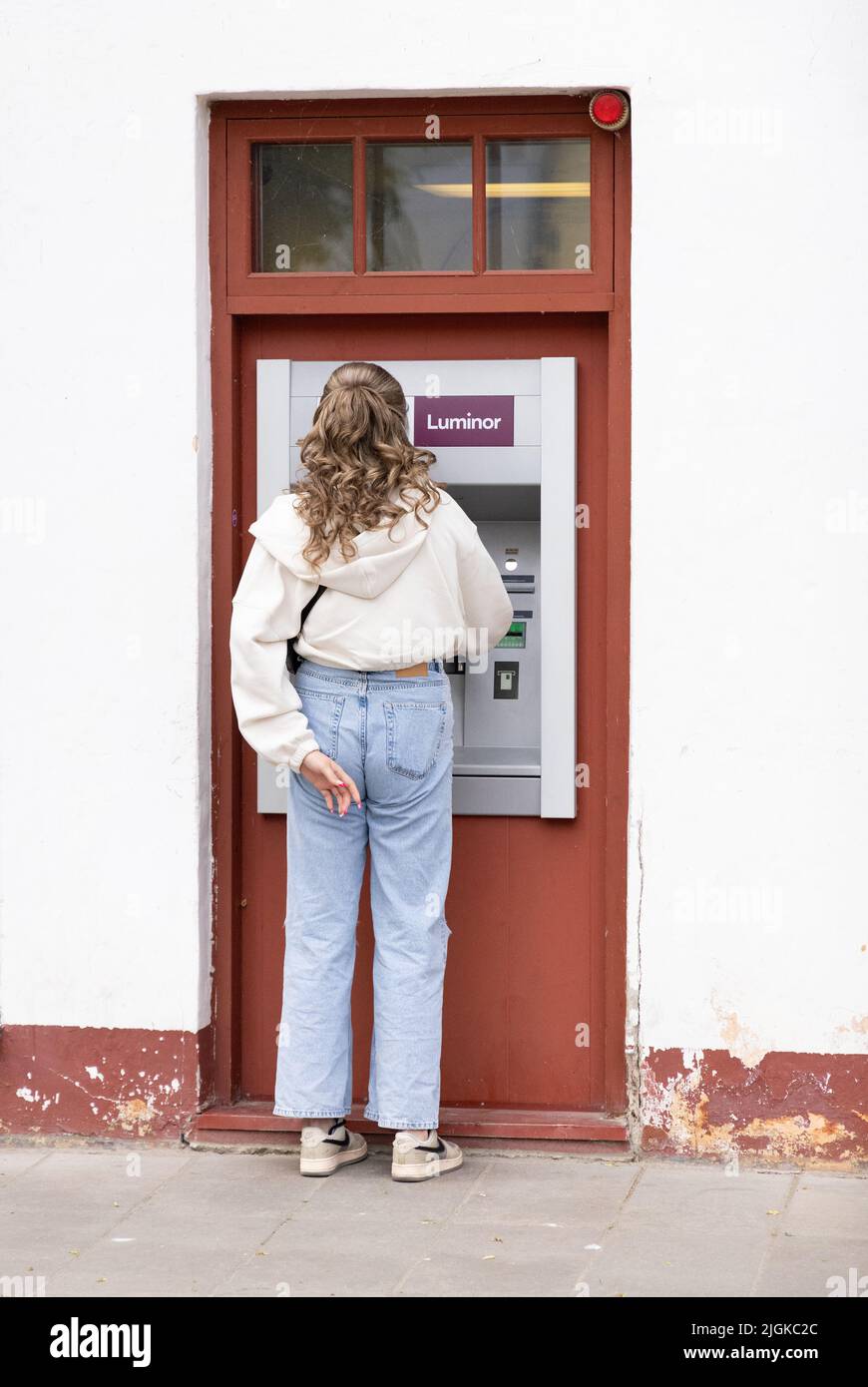 Banco de Estonia - vista trasera de una mujer que obtiene dinero en efectivo de un cajero automático del Banco Luminor, Kuressaare, Estonia, Estados Bálticos, Europa Foto de stock