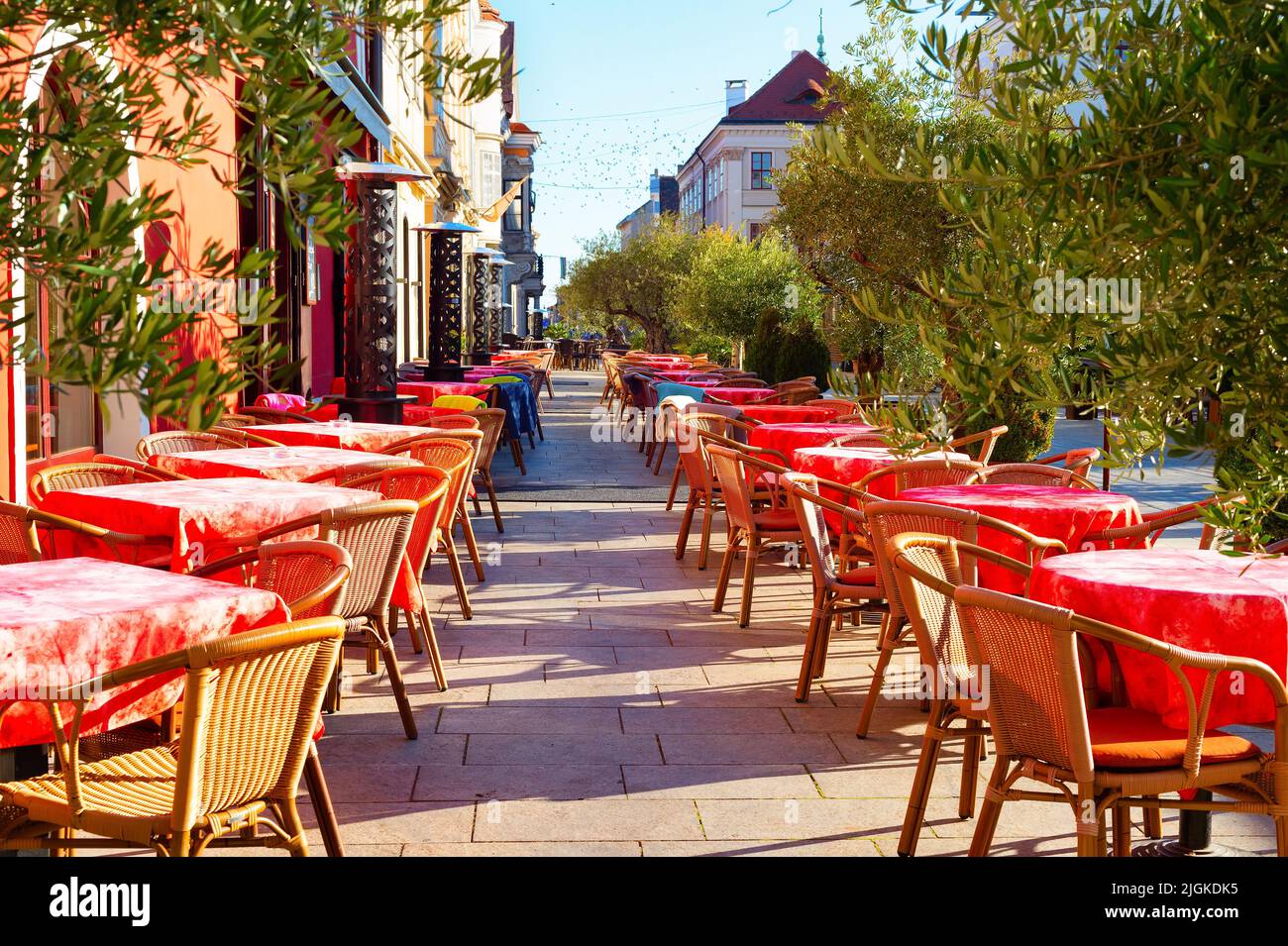 Mesas con telas rojas en la terraza exterior del restaurante en la calle turística, Gyor, Hungría Foto de stock