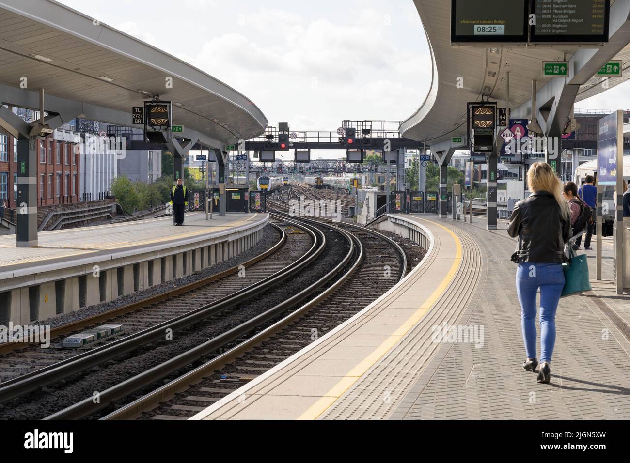 Pasajeros camina en la plataforma para su próximo tren a casa en el día soleado de Londres Puente estación Inglaterra Reino Unido Foto de stock