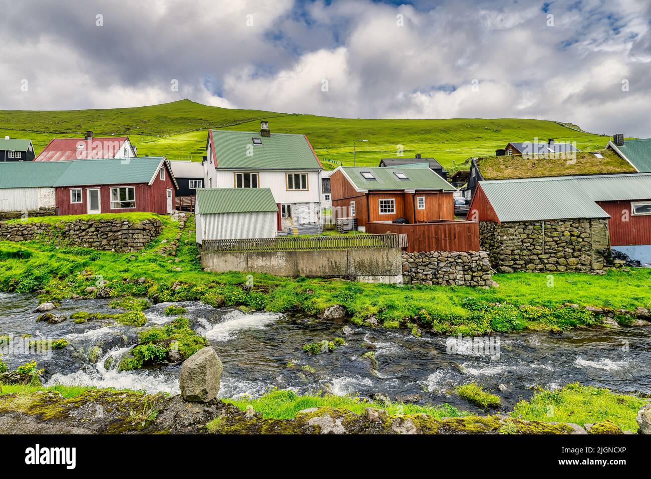 Coloridas casas del pueblo de Gjogv y un pequeño río desemboca en el fiordo. Islas Feroe Foto de stock