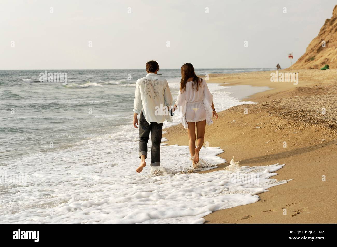 Una joven pareja romántica camina de la mano en la playa Foto de stock