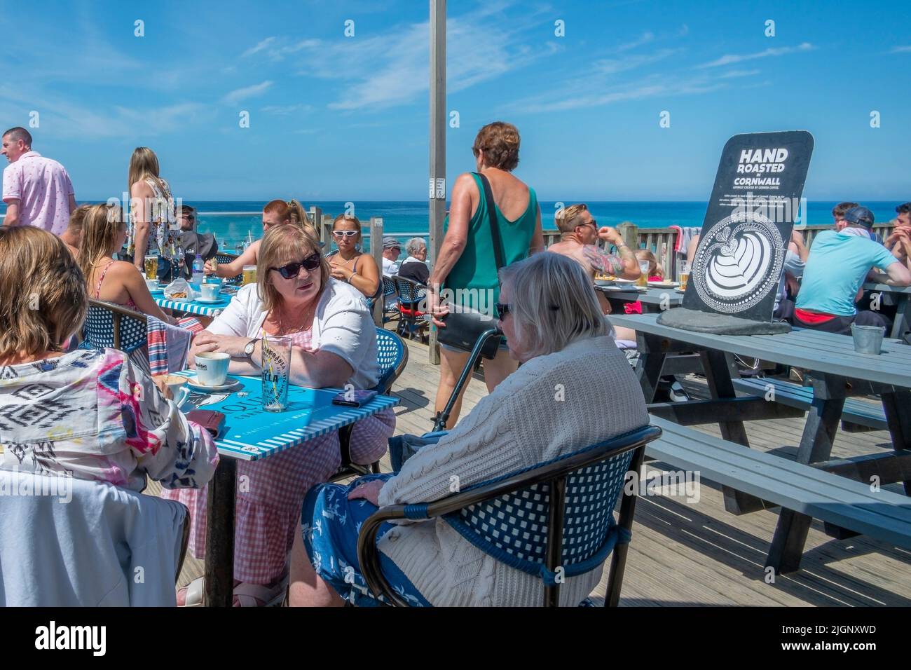 Los turistas que socializan en la zona de terrazas del Fistral Beach Bar en Fistral en Newquay en Cornwall en el Reino Unido. Foto de stock