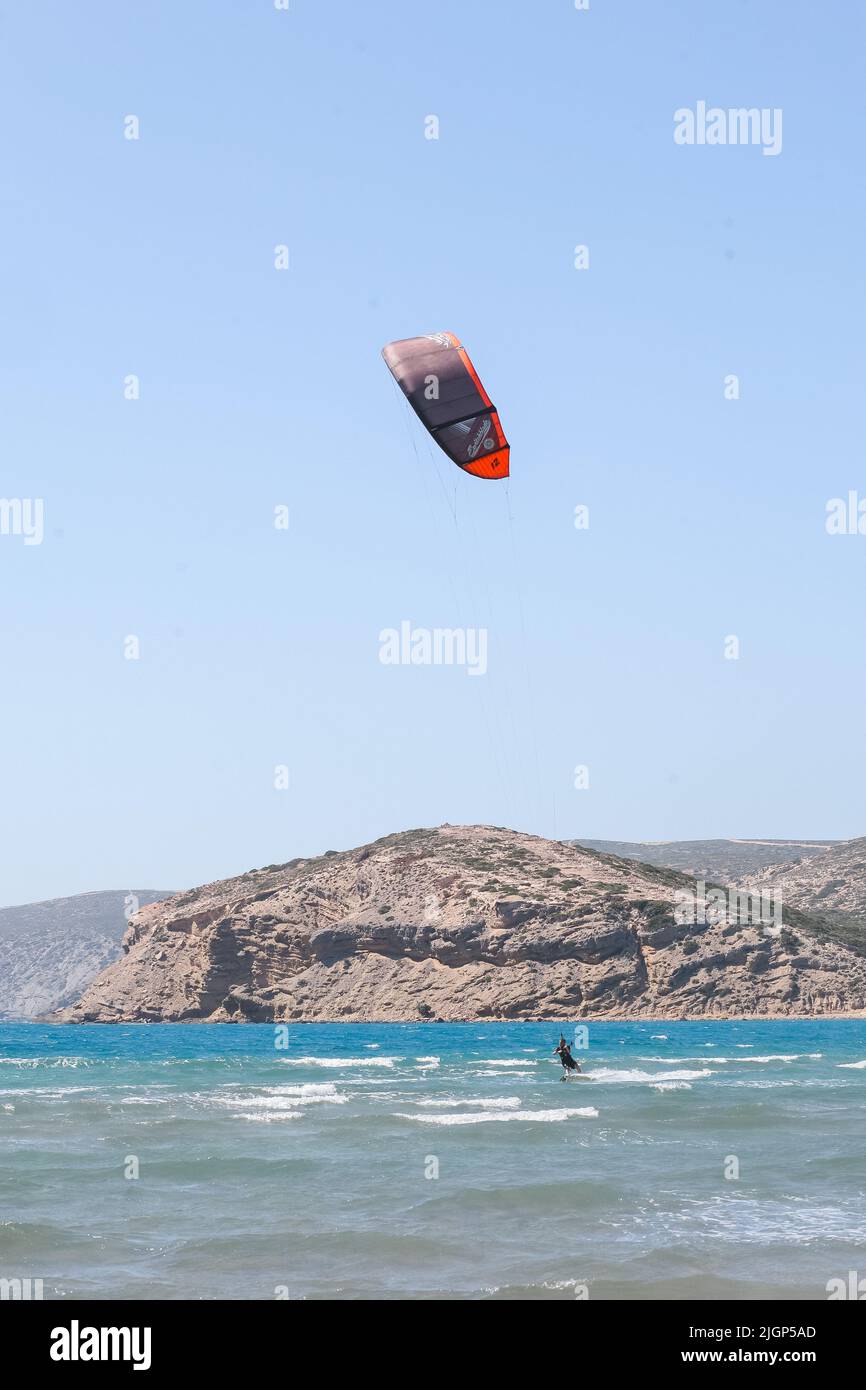 Surfista profesional de kite surfista en una tabla con una tabla en un lago con agua de mar al atardecer. Salpicaduras de agua y reflejo del sol. Deportes acuáticos. Vista panorámica Foto de stock